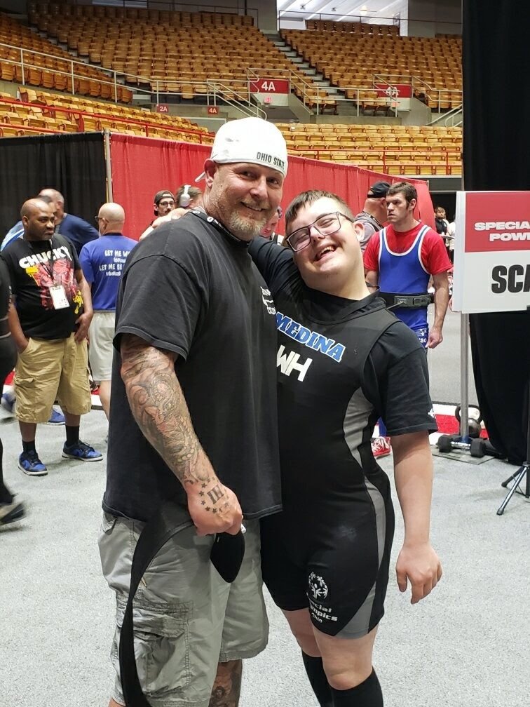 A Flash coach and powerlifter share a hug at competition.