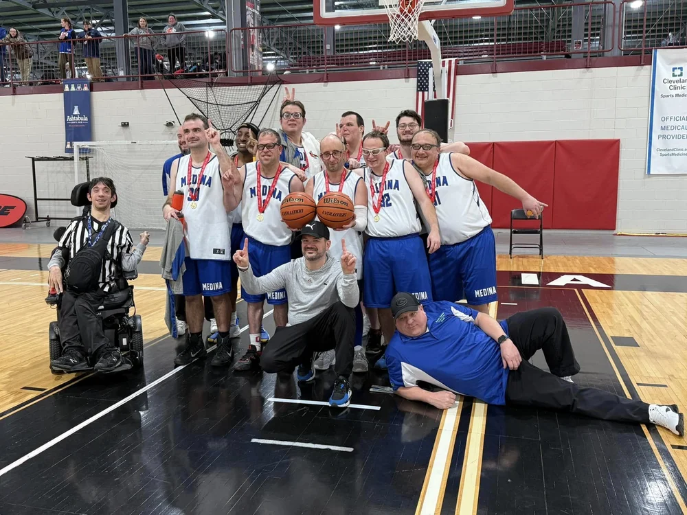 The Flash basketball team celebrating together on the court with their medals.