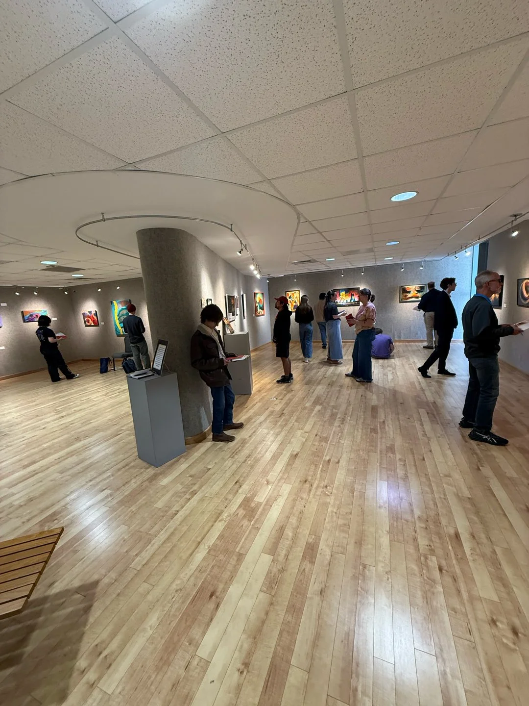 Workshop students viewing artwork, listening through earbuds, and composing haiku at Brazosport College.