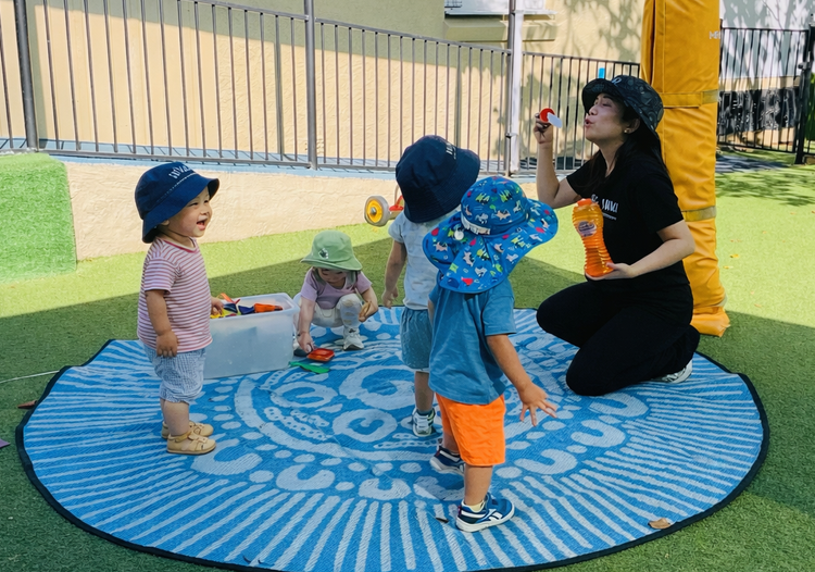 Kelvin educator leading outdoor play with a small group of children