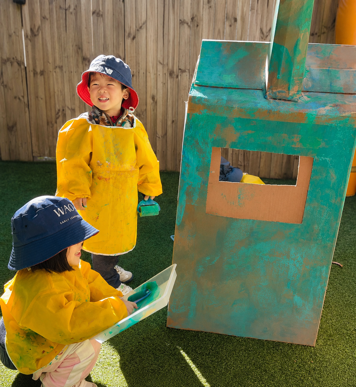 Toddlers enjoying imaginative outdoor play together at Kelvin Kindergarten St Ives