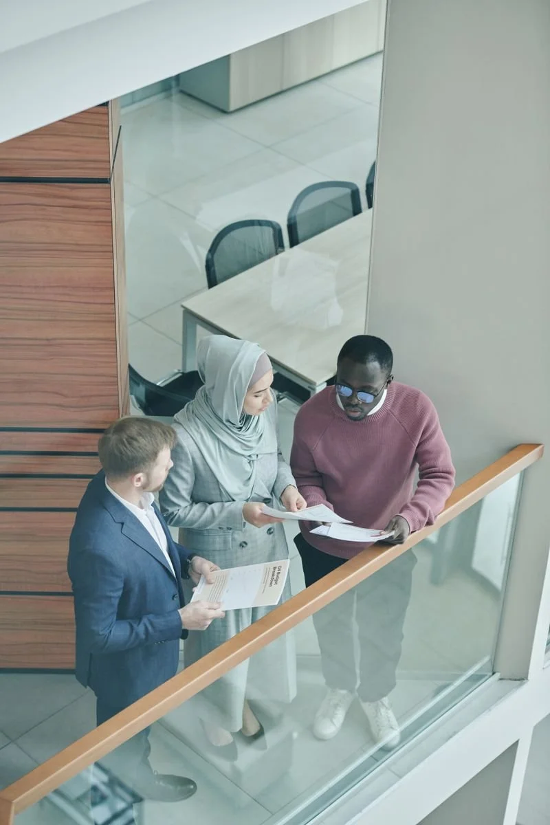 Three colleagues discussing printed information beside a staircase