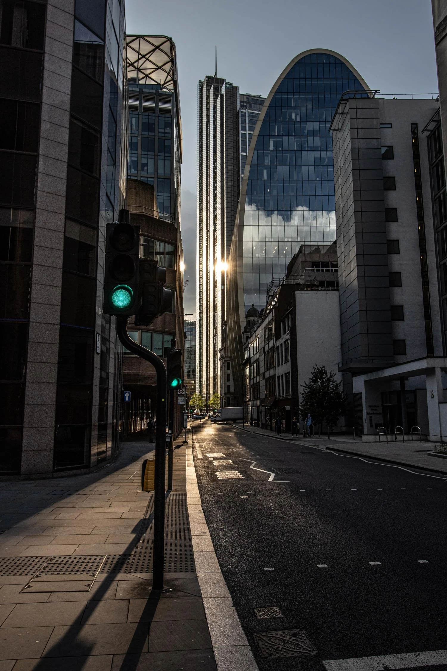 Rua entre prédios contemporâneos, iluminada pelo sol