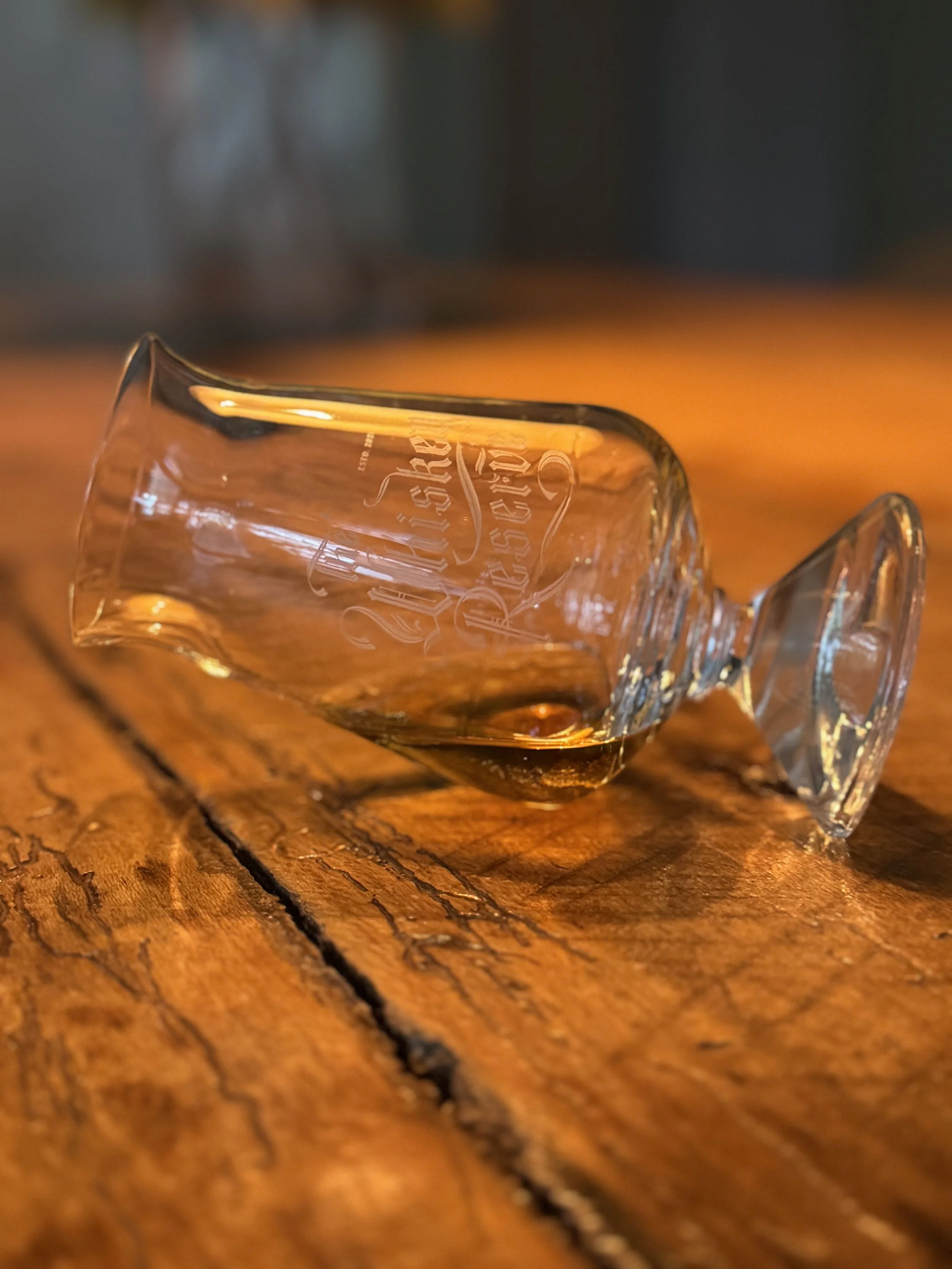 An Irish whiskey glass on its side with some gold colored whiskey in the glass