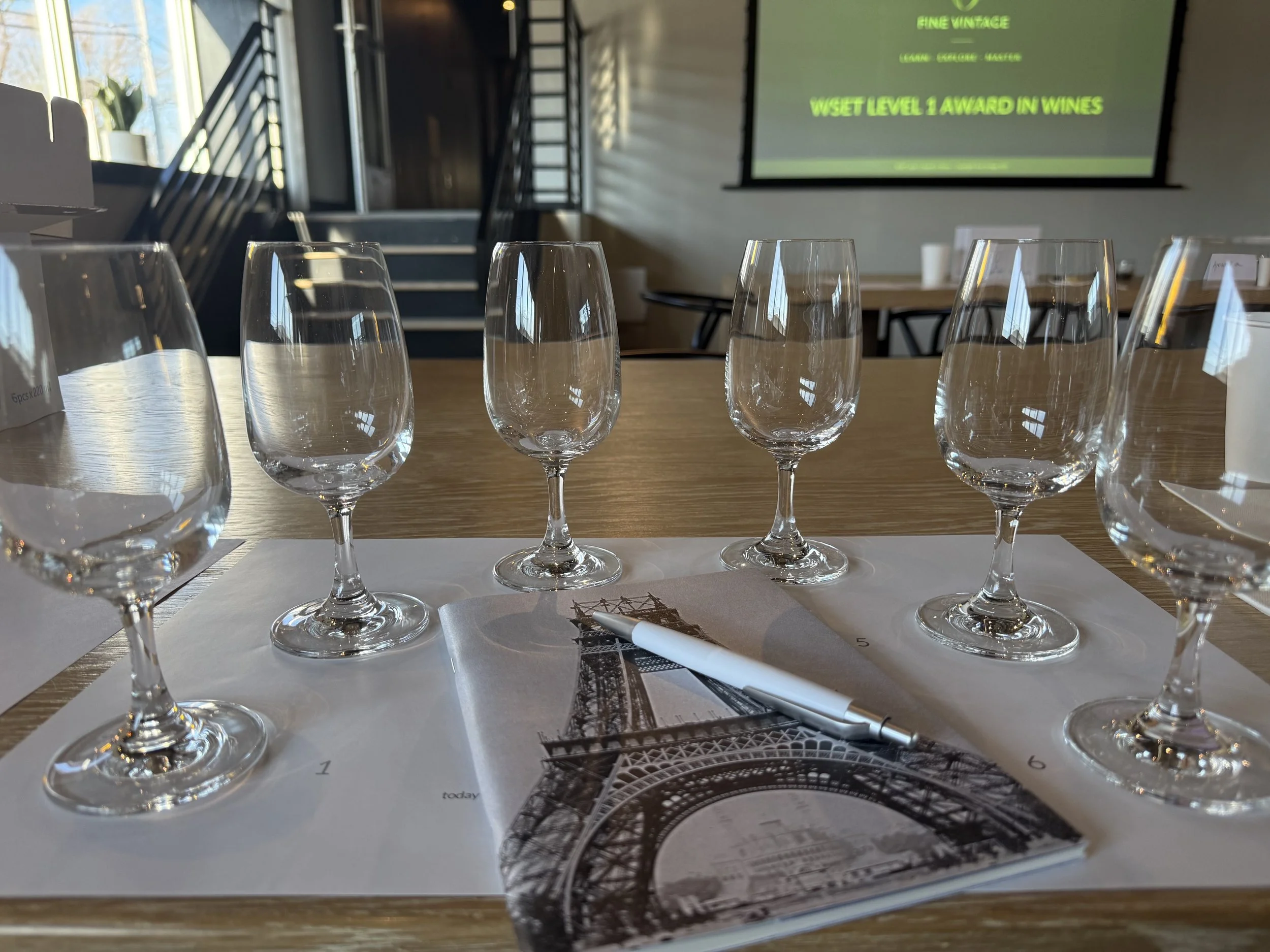 Tasting wine glasses on a tasting mat featuring a notebook with the Eifel Tower
