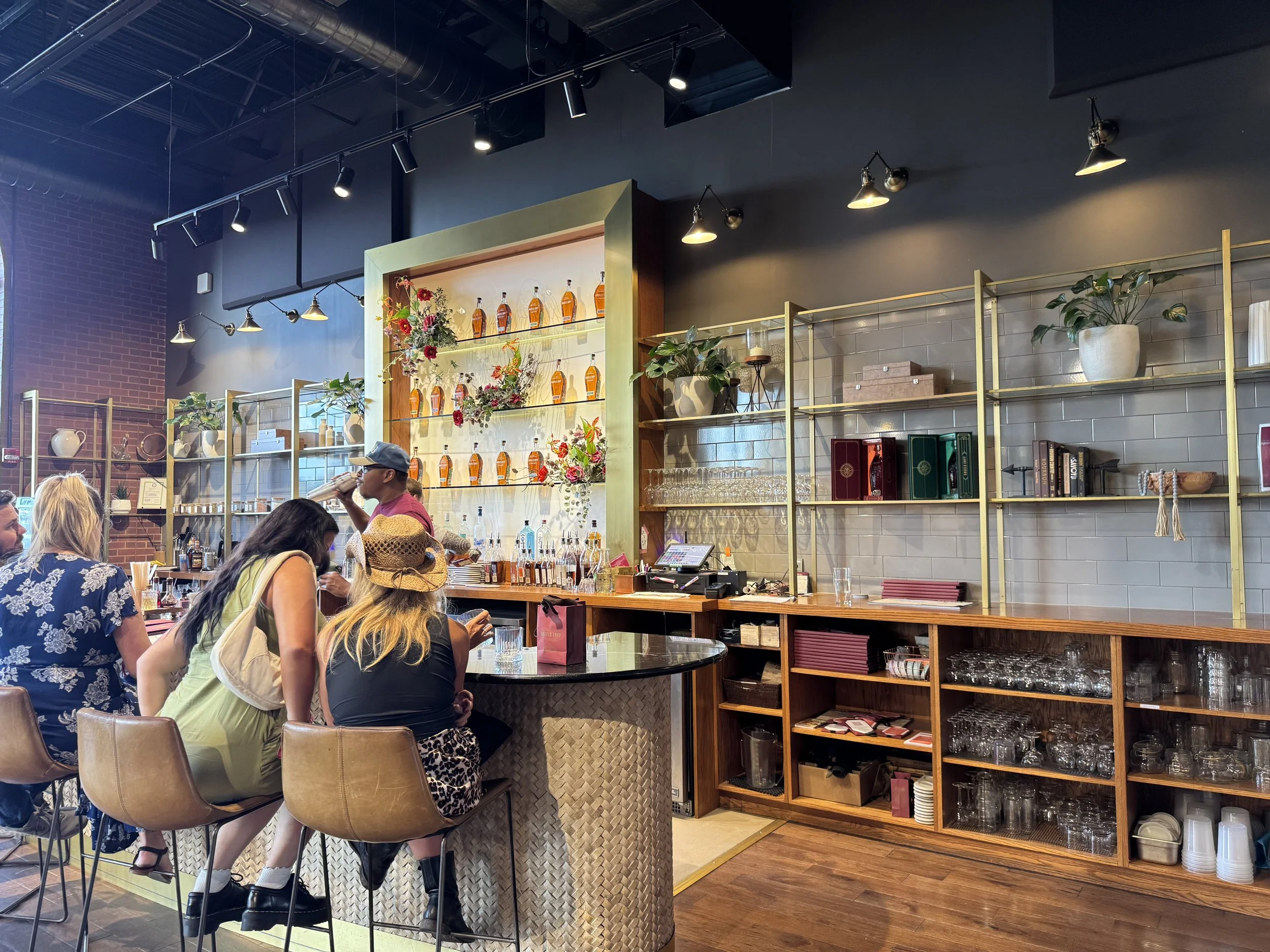 Angel's Envy Bar, featuring a bartender shaking a cocktail and many whiskey bottles on the shelves behind.