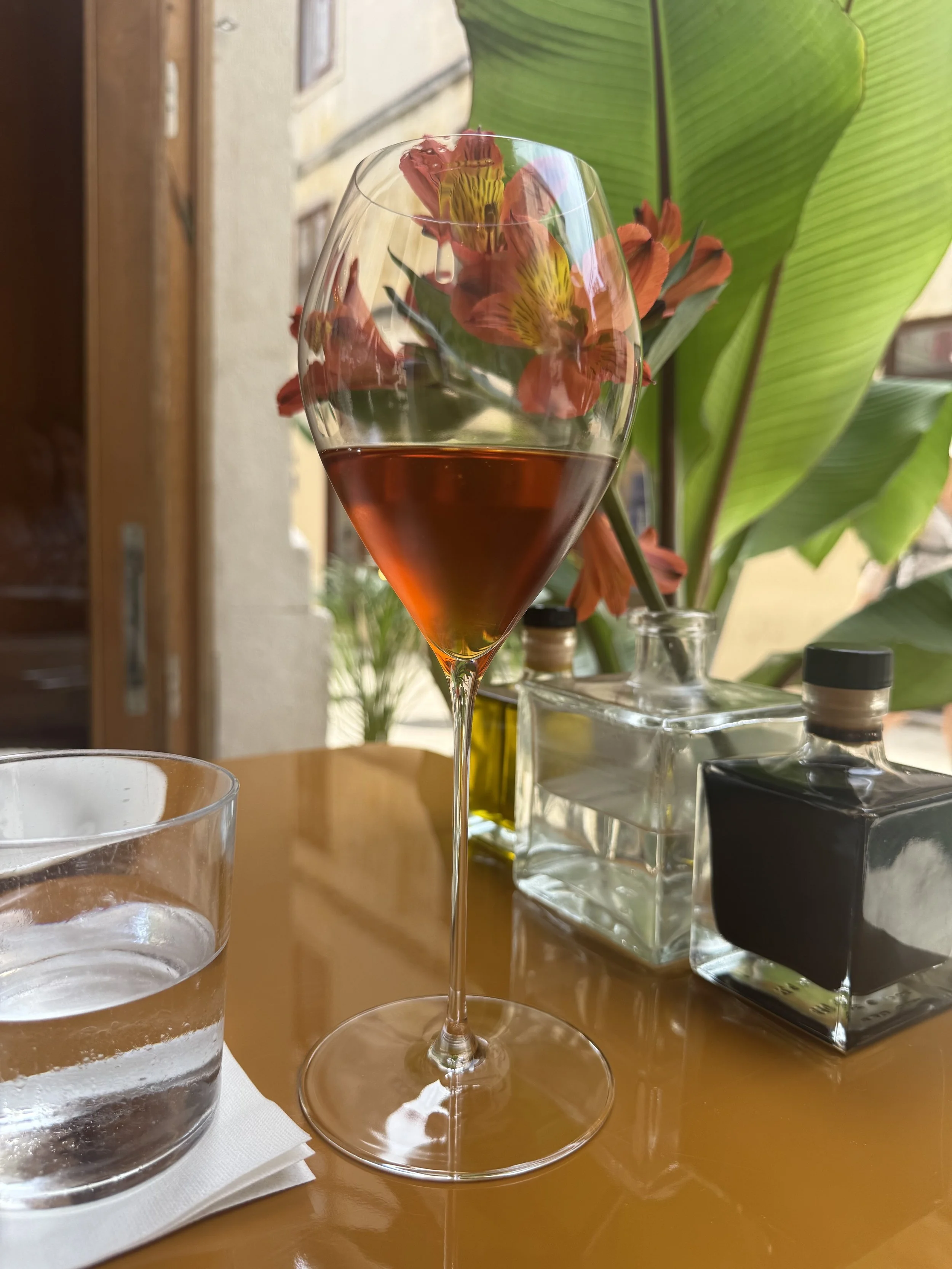 Dessert wine glass filled with a rose, amber color wine that matches flowers on a dining table