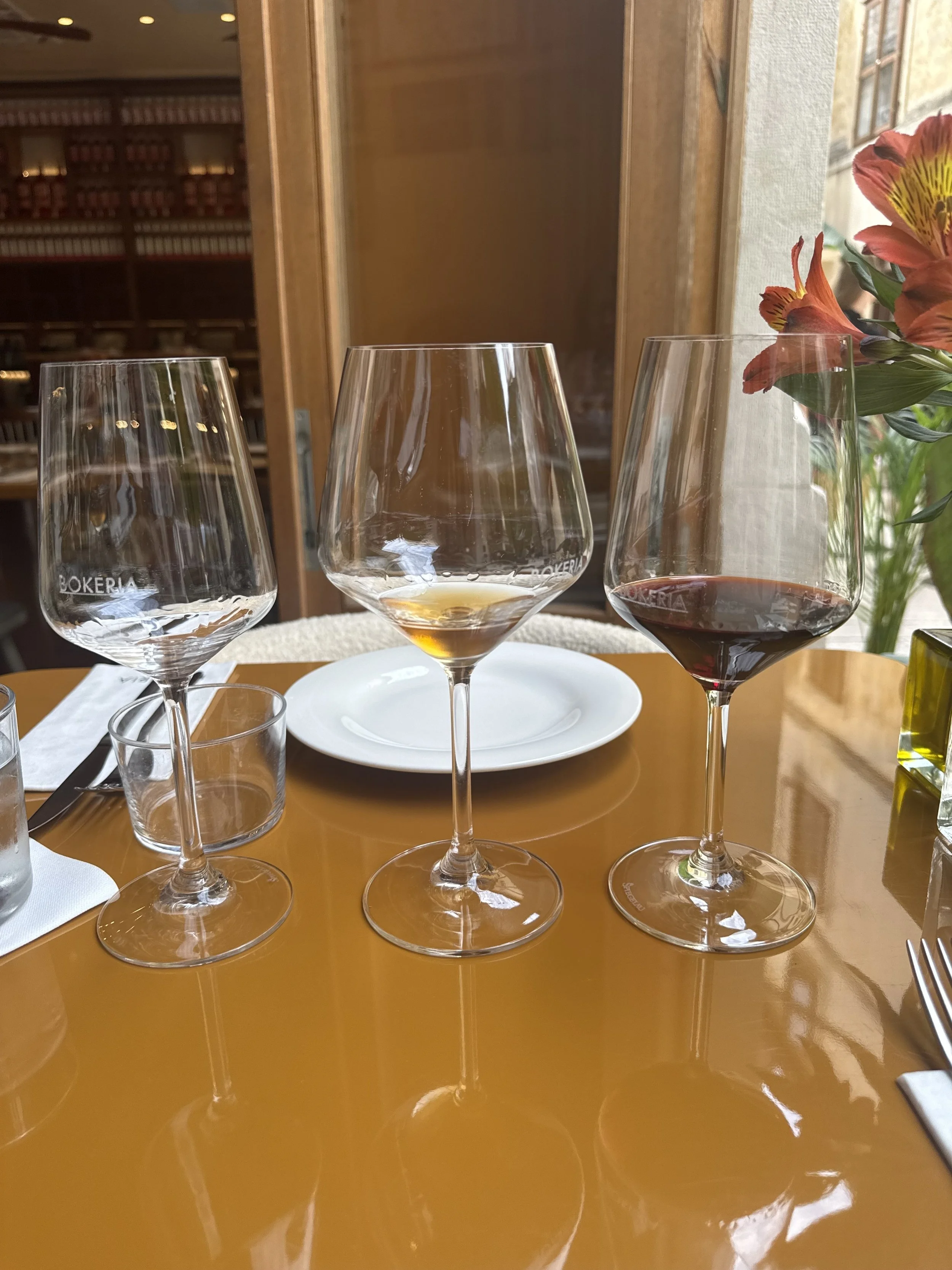 Wine glasses one empty, one filled with a gold color wine, and with a red wine