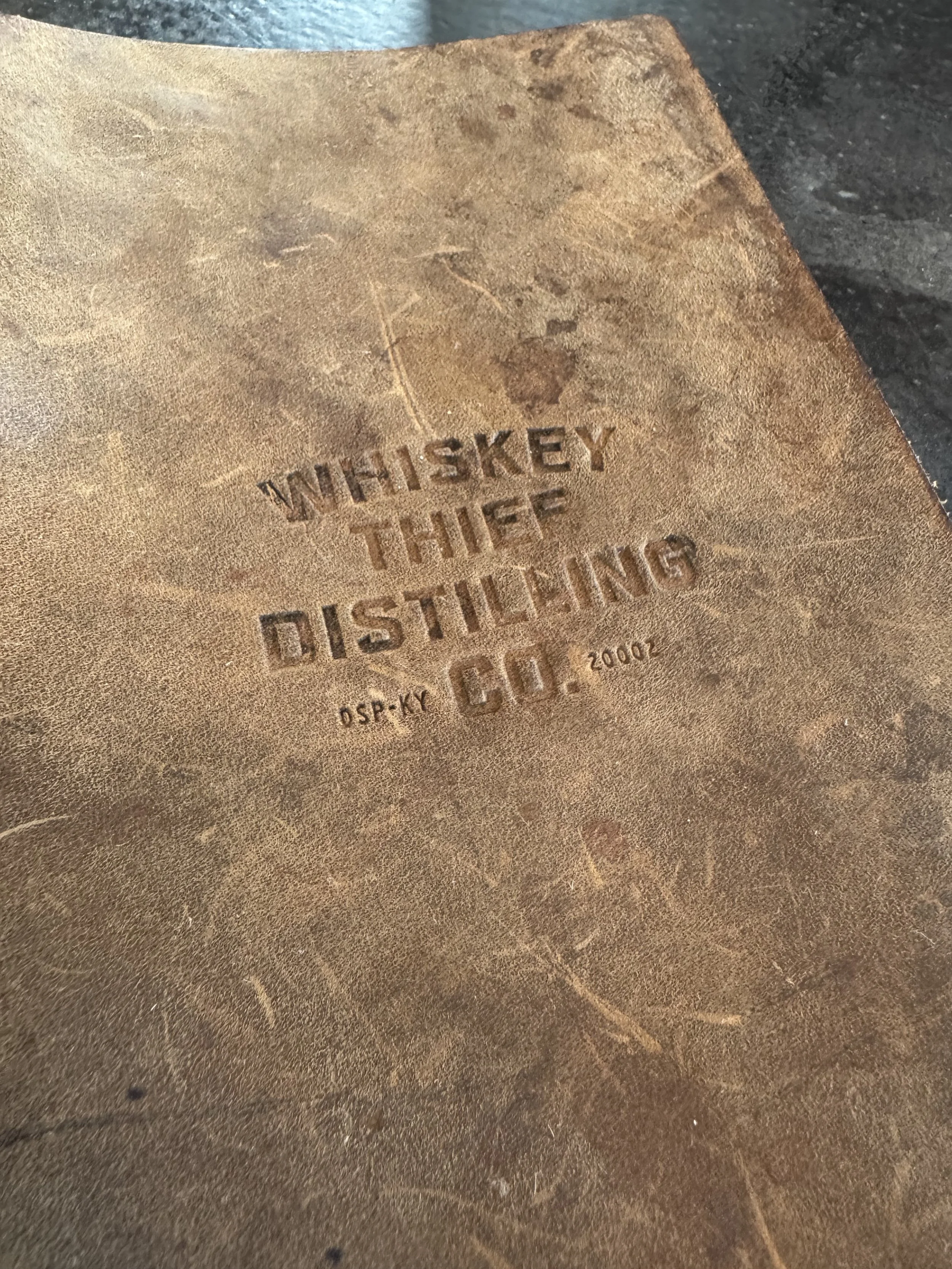 A rustic menu cover with Whiskey Thief Distilling Co. imprinted on it