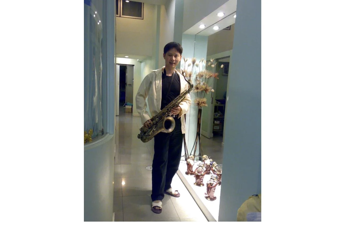 Dr. Rushapol Sdawat standing in a corridor holding a tenor saxophone