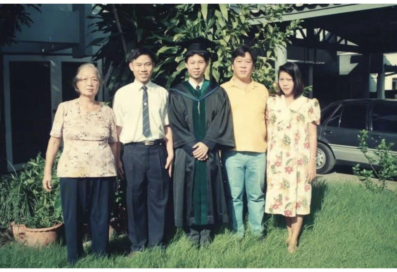 Dr. Rushapol Sdawat in his graduation gown standing with family members in a garden