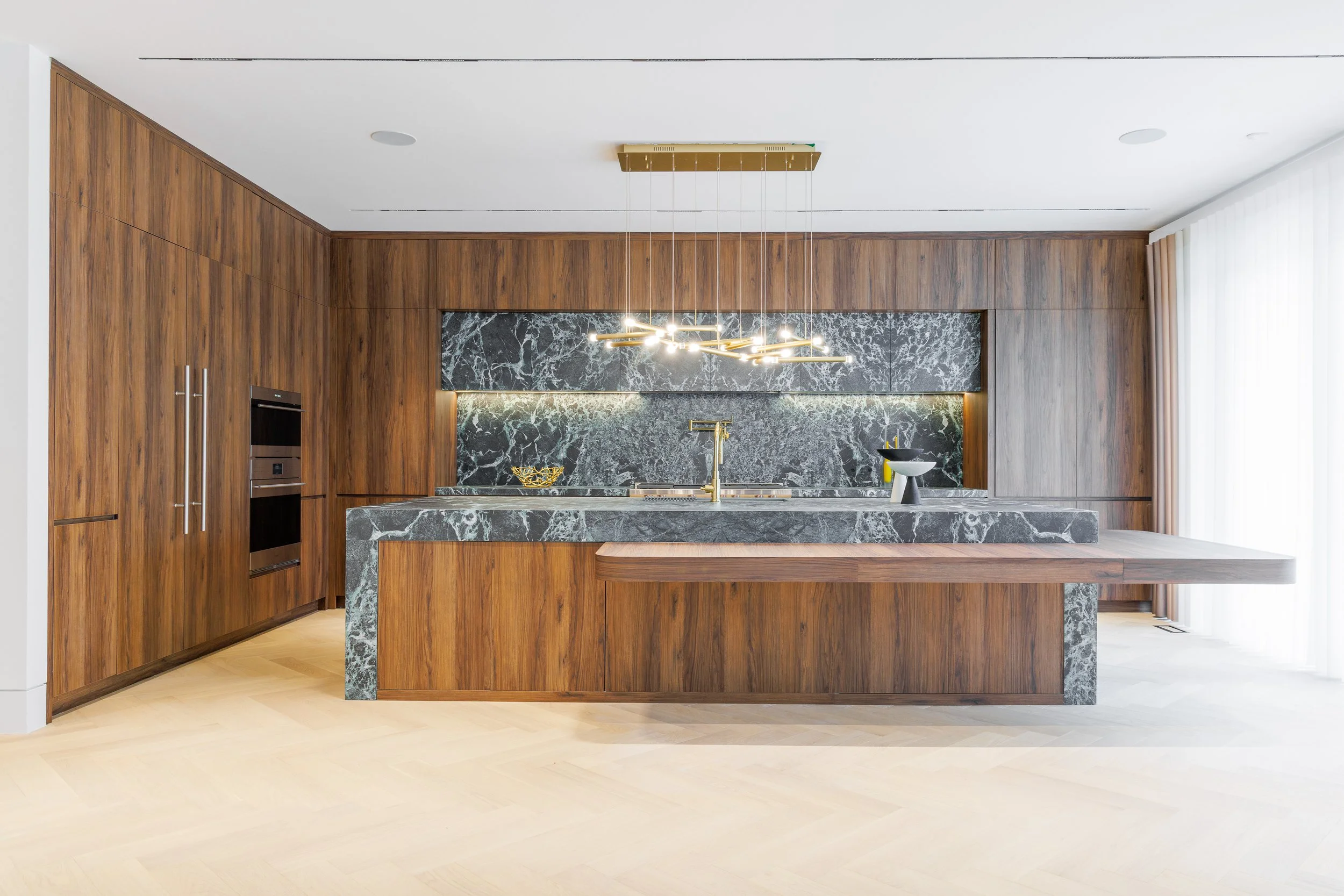 Church Street Residence kitchen with a green marble island and cantilevered walnut dining table, without chairs.