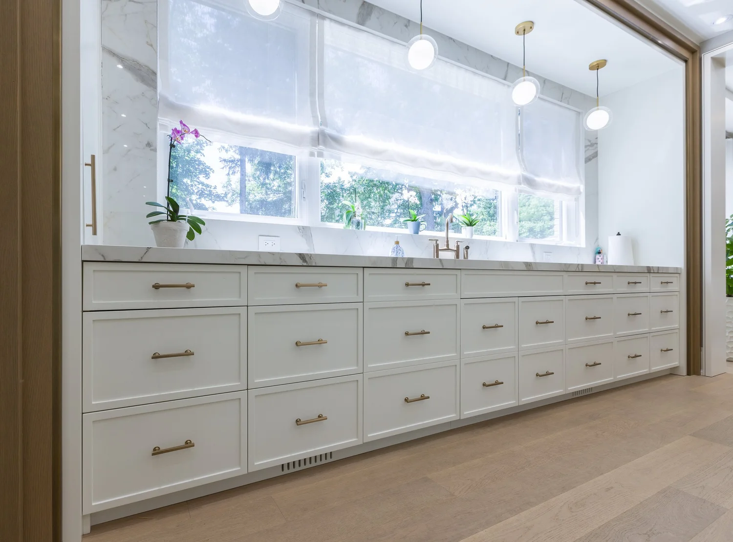 Drawer run beneath the window wall with brass pulls and a marble counter.