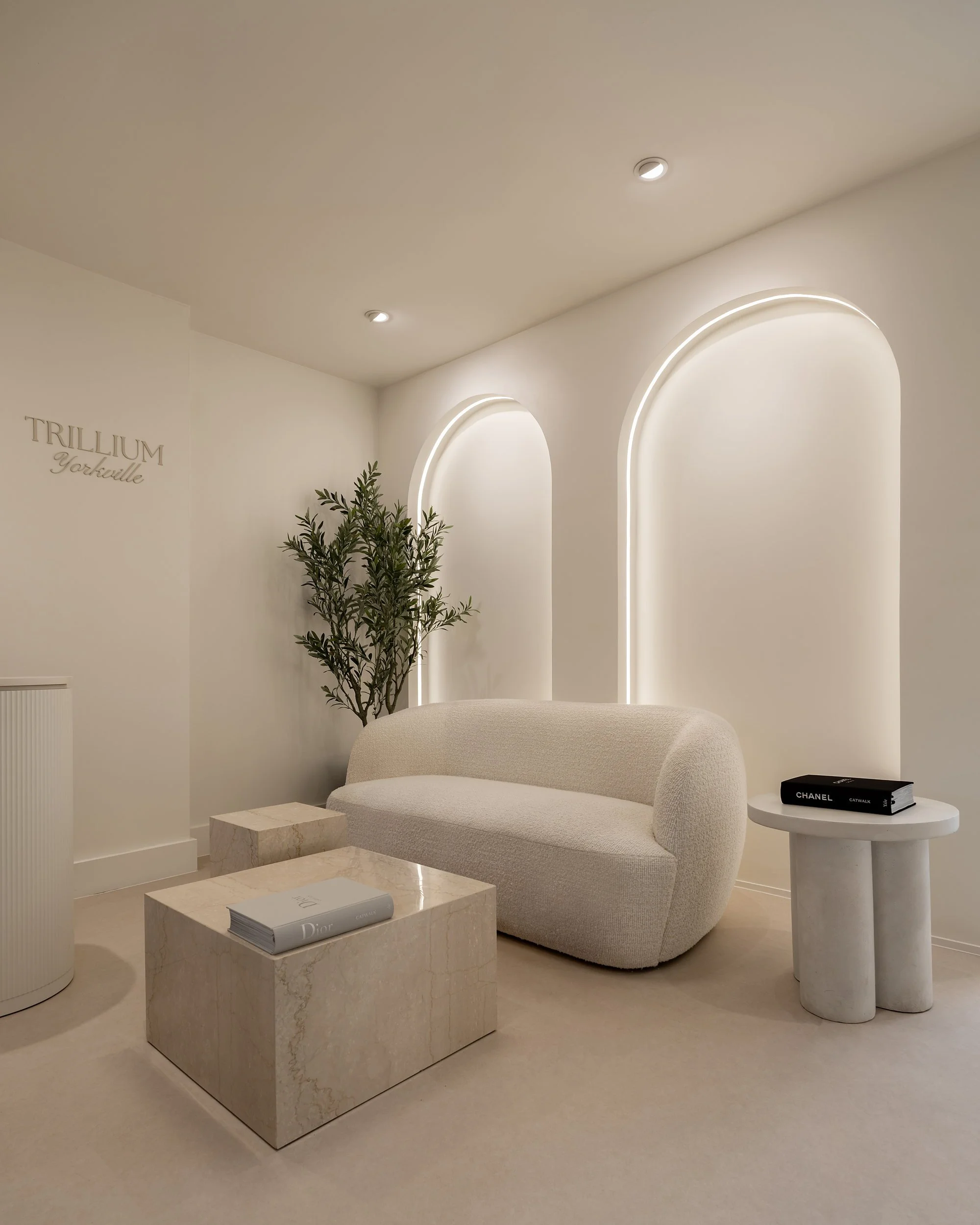 Reception lounge with arched backlit niches, curved sofa, and stone plinth tables.