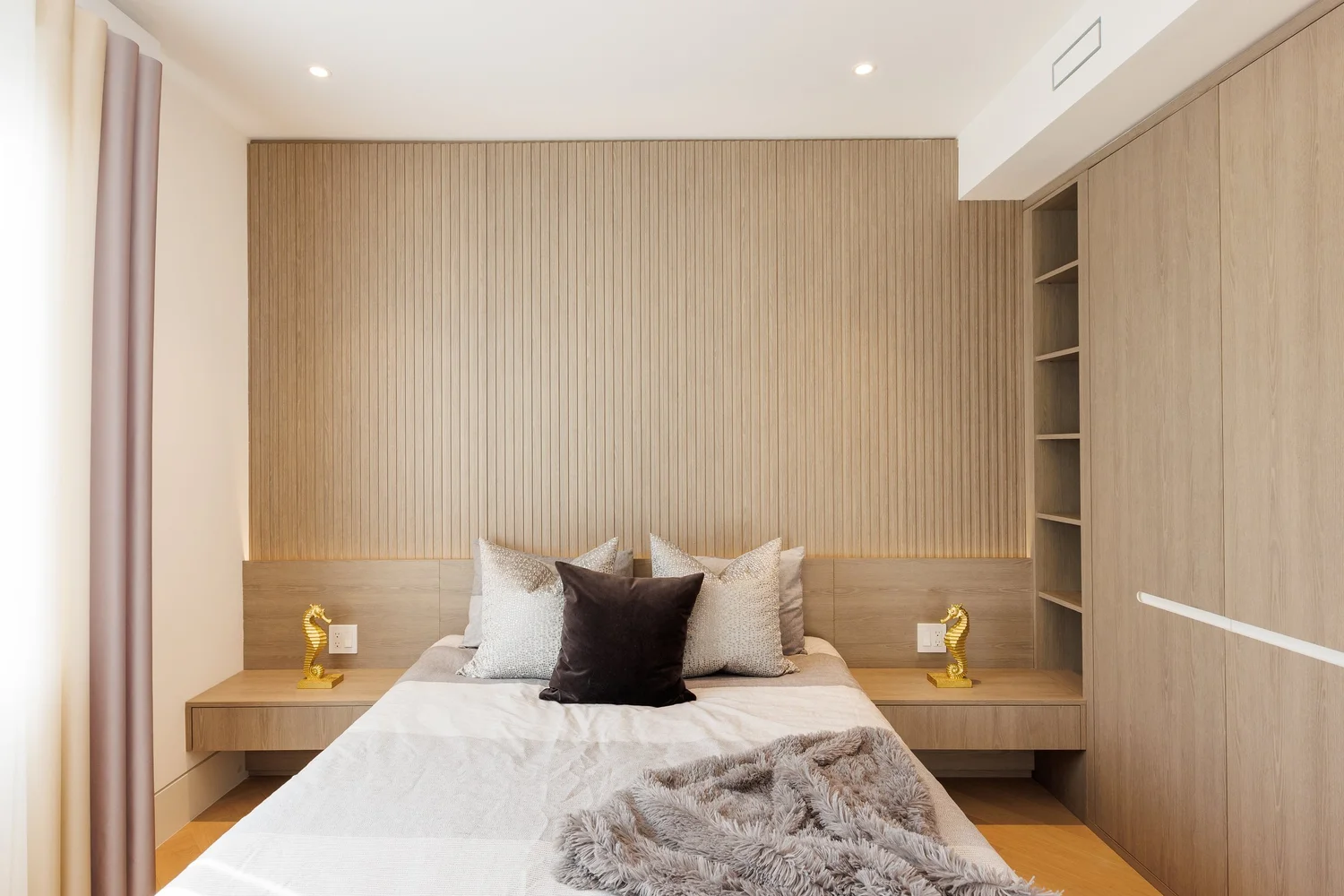 Bedroom with a slatted oak headboard wall, floating nightstands, and a built-in wardrobe.
