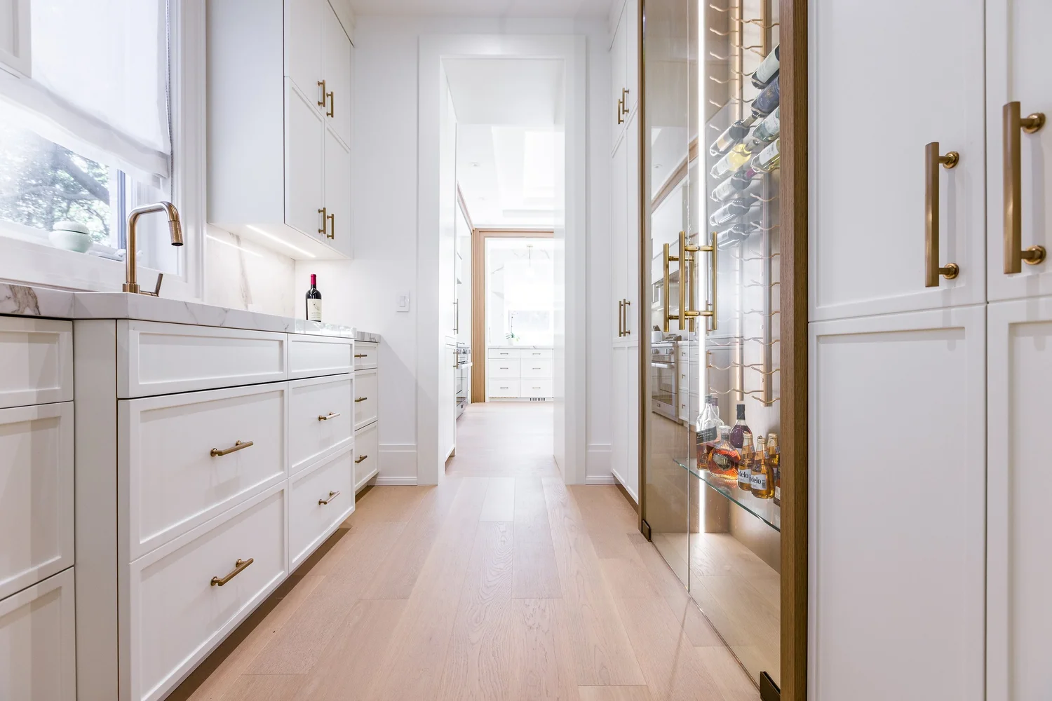Butler's pantry with a glass-fronted wine display and brass hardware.