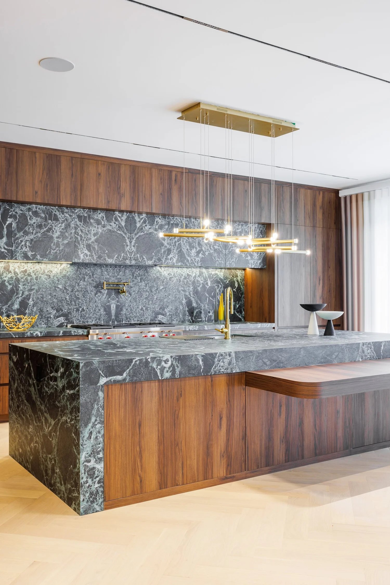 Green marble island with its cantilevered walnut table, seen from the entry.