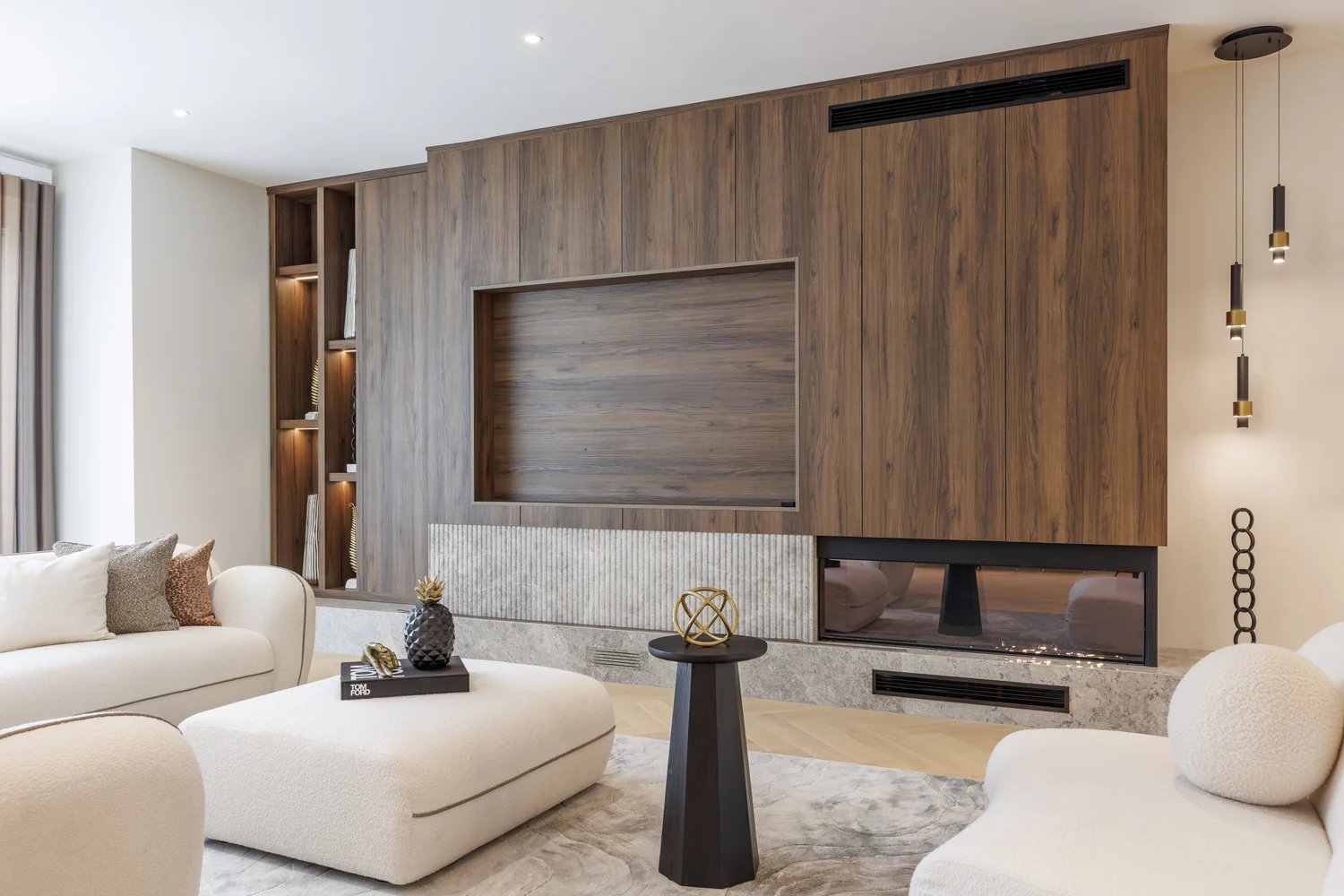 Living room media wall in walnut with a fluted stone plinth and linear fireplace.
