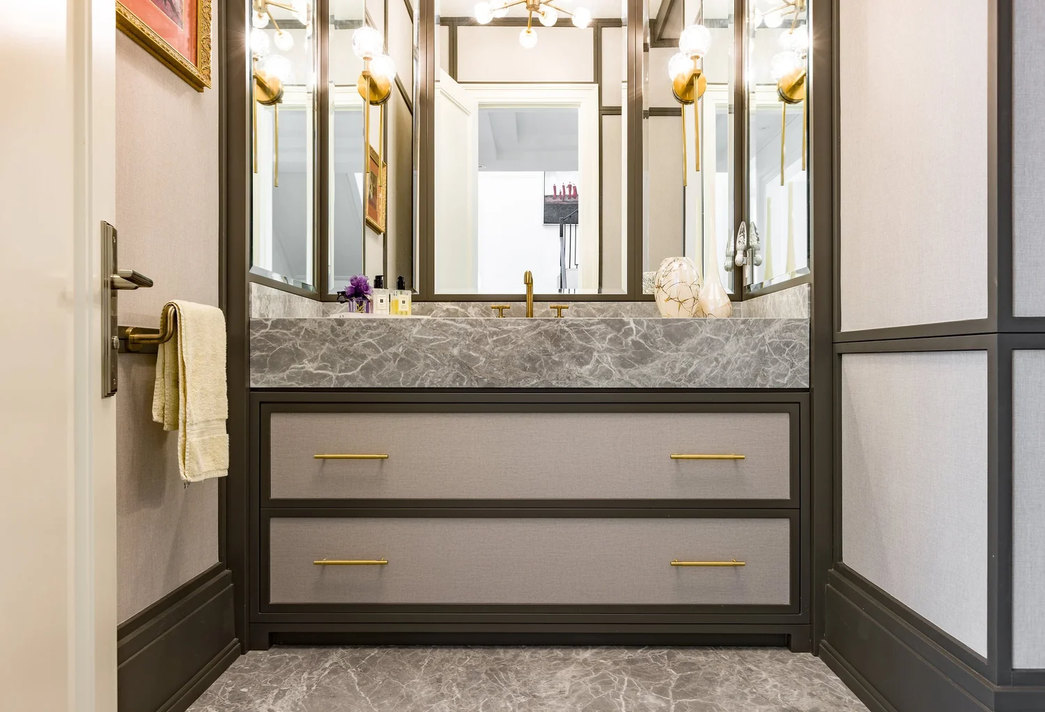 Powder room with a grey stone vanity and mirrored panelled walls.