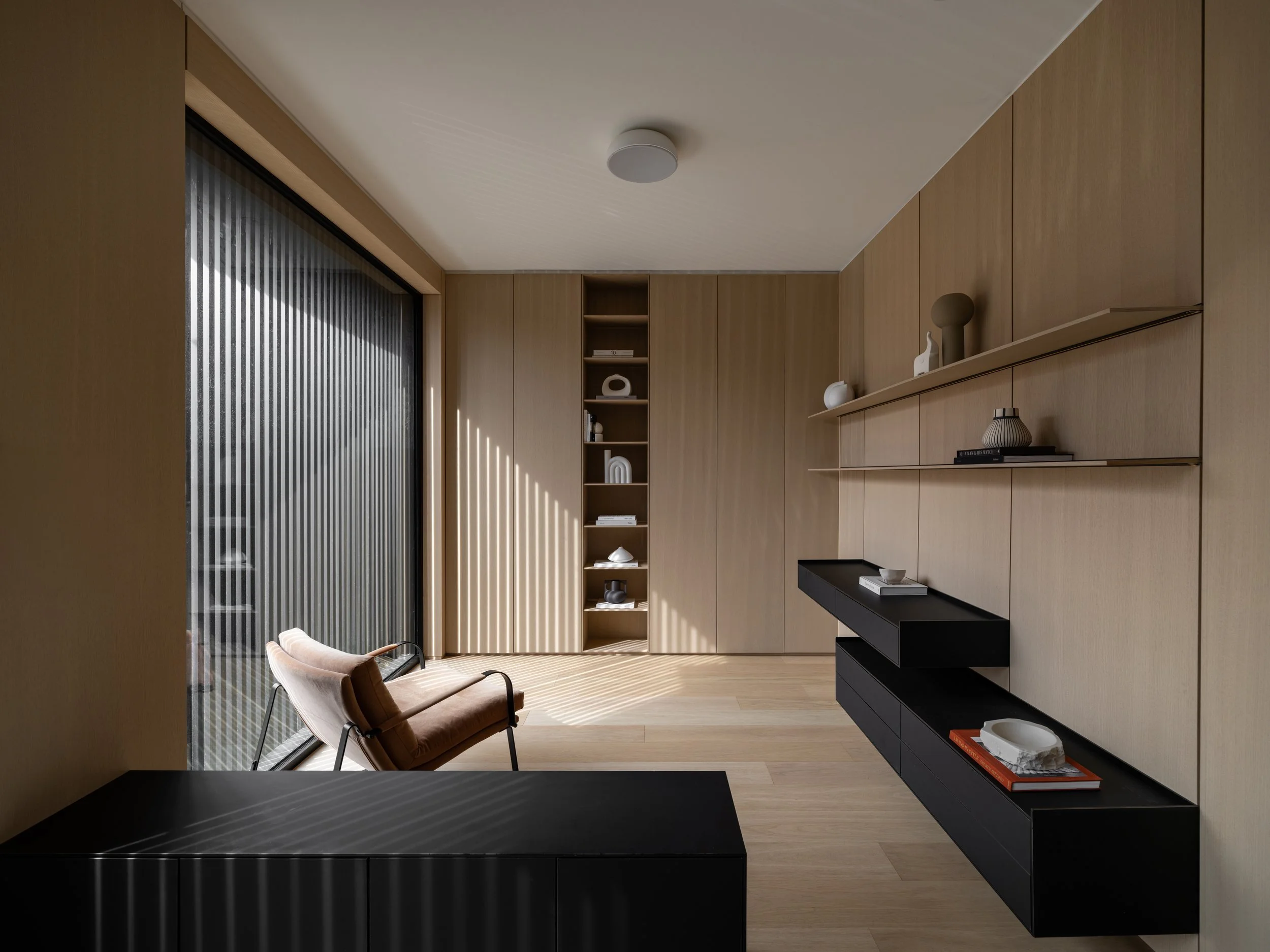 Main-floor Montclair office with full-height oak panelling, open shelving, and floating black cabinetry.