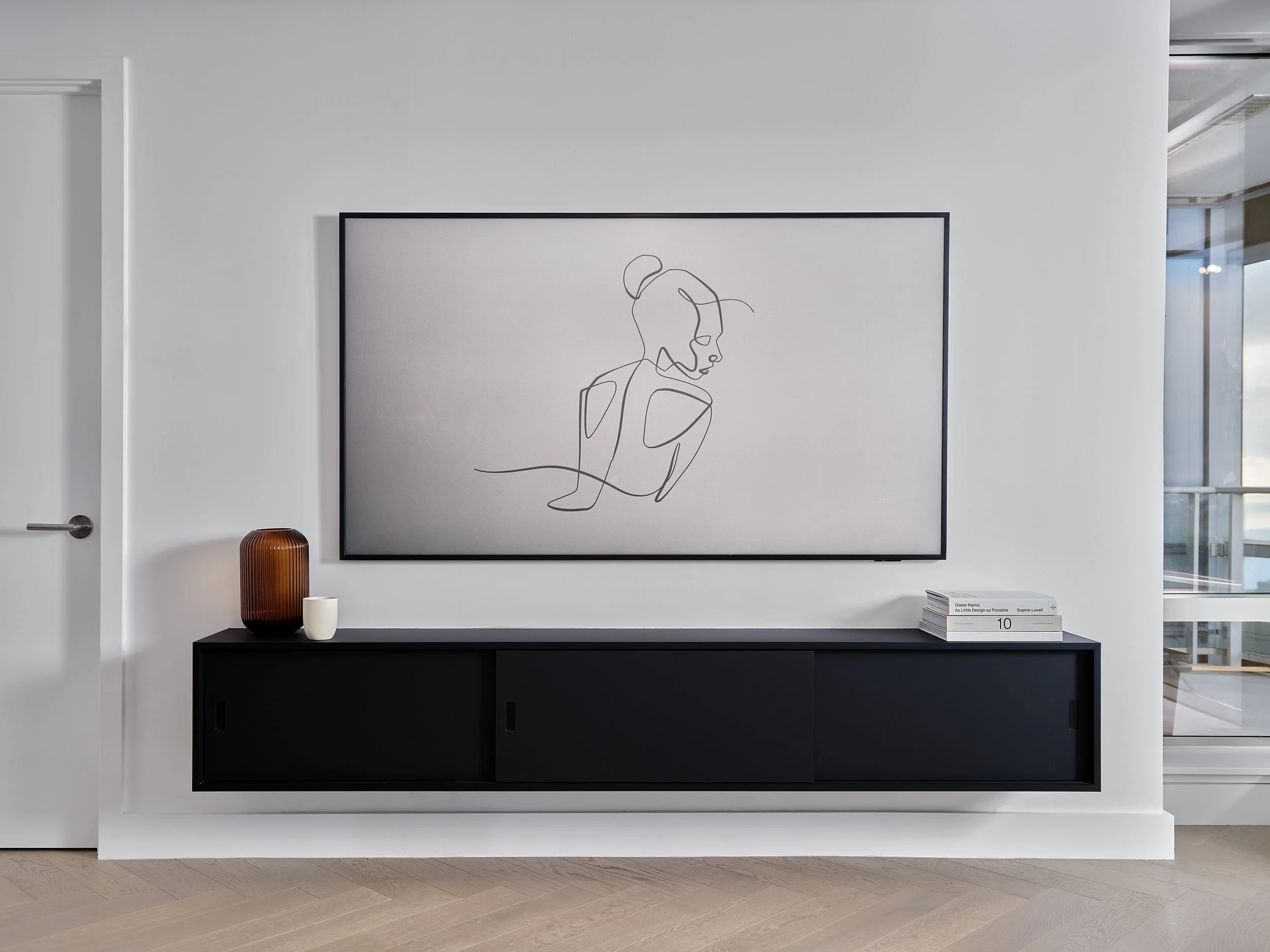Floating black media console and framed television on a white wall.