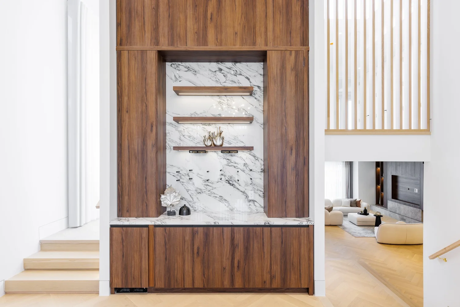 Walnut bar niche with a marble backsplash and shelving in the double-height hall.