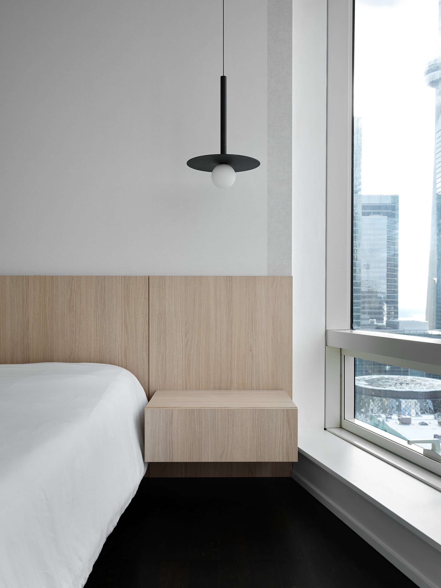 Bedroom with white oak headboard wall and integrated floating nightstand.
