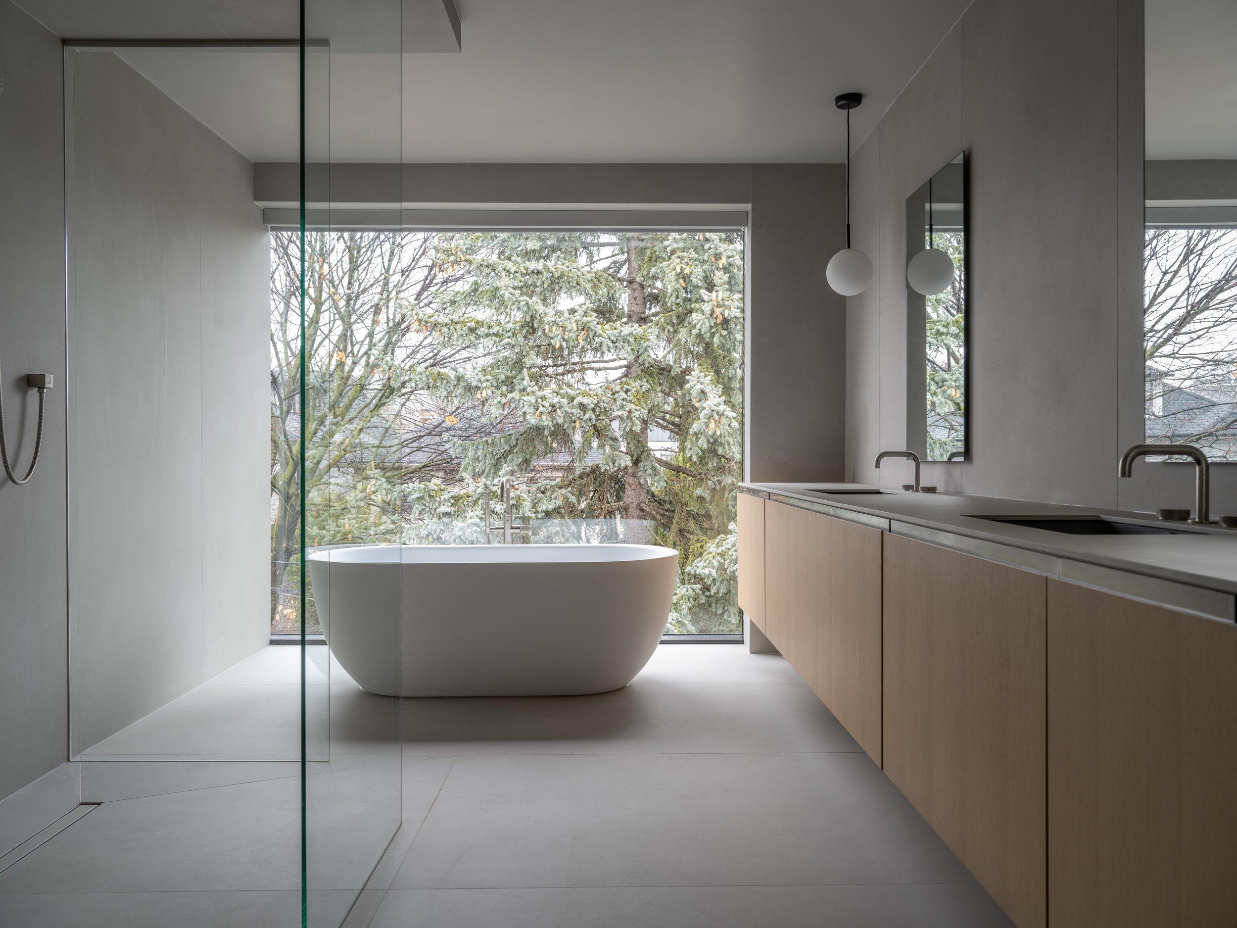 Primary bathroom with freestanding bathtub and floating oak vanity by the window.