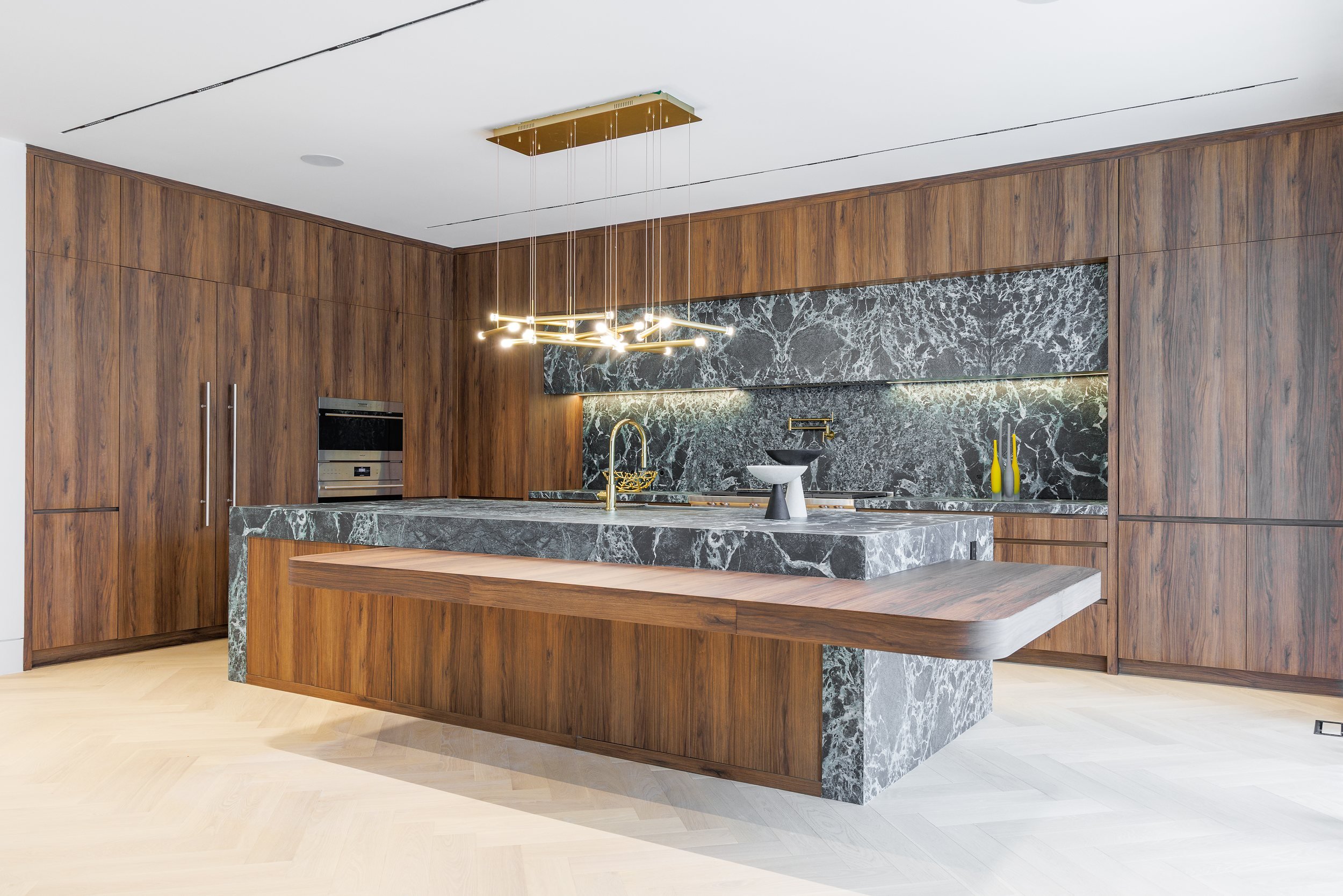 Church Street Residence kitchen with full-height walnut cabinetry, a green marble island, and a cantilevered walnut dining table.