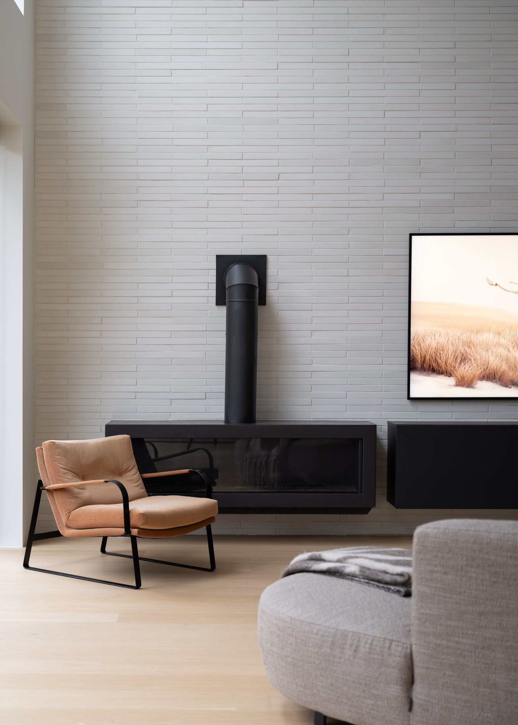 Great room with an exposed white brick wall, black fireplace, floating media cabinetry, and television.