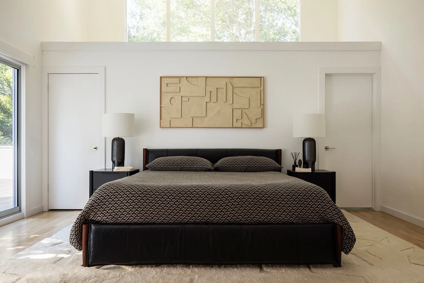 Modern primary bedroom, leather bed, high ceilings
