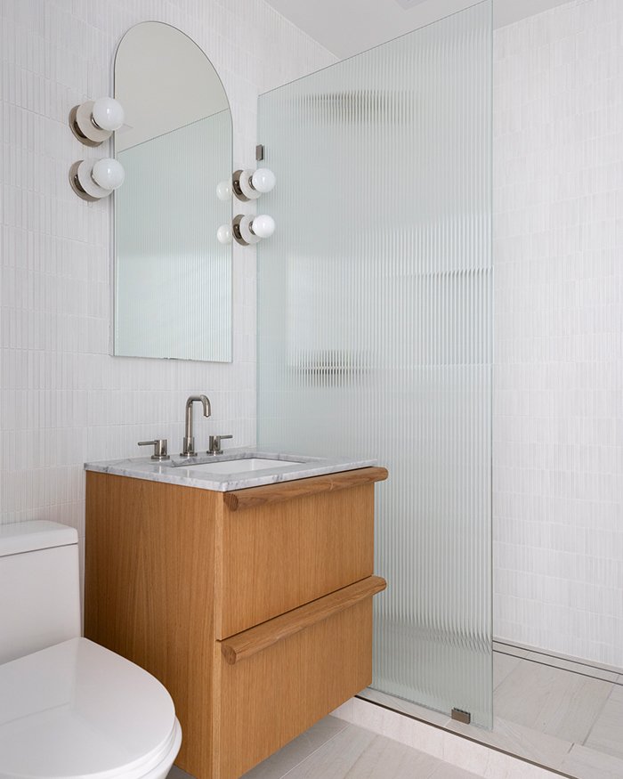 Modern white bathroom, floating wood vanity, fluted glass shower