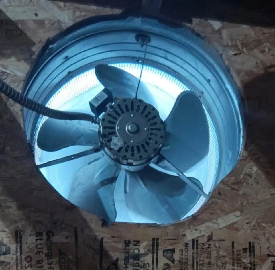 Gable fan set among the rafters and sheathing of an attic in an older Norfolk, VA house