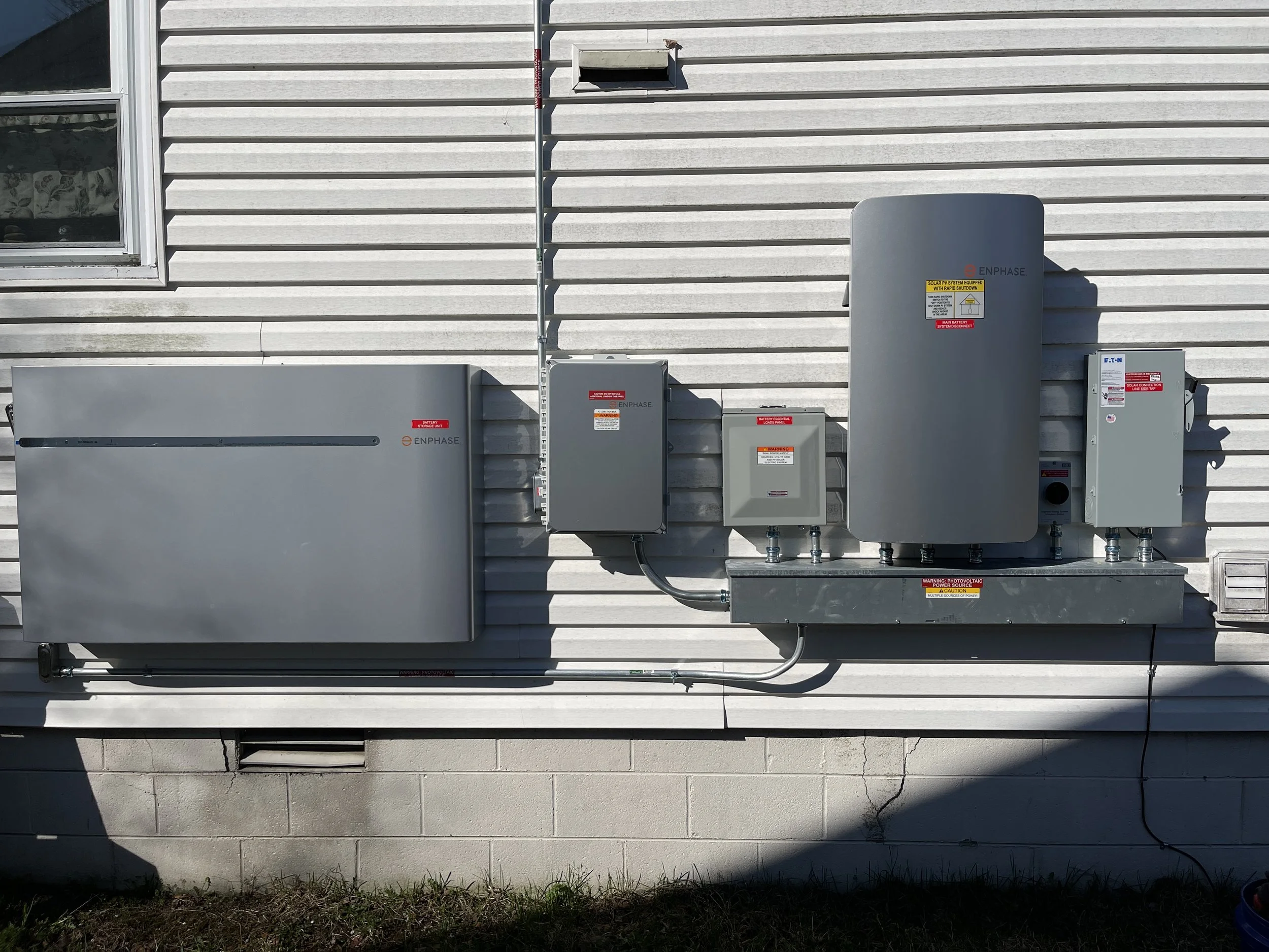 Commercial meters and disconnects mounted on a raised concrete base at a building wall