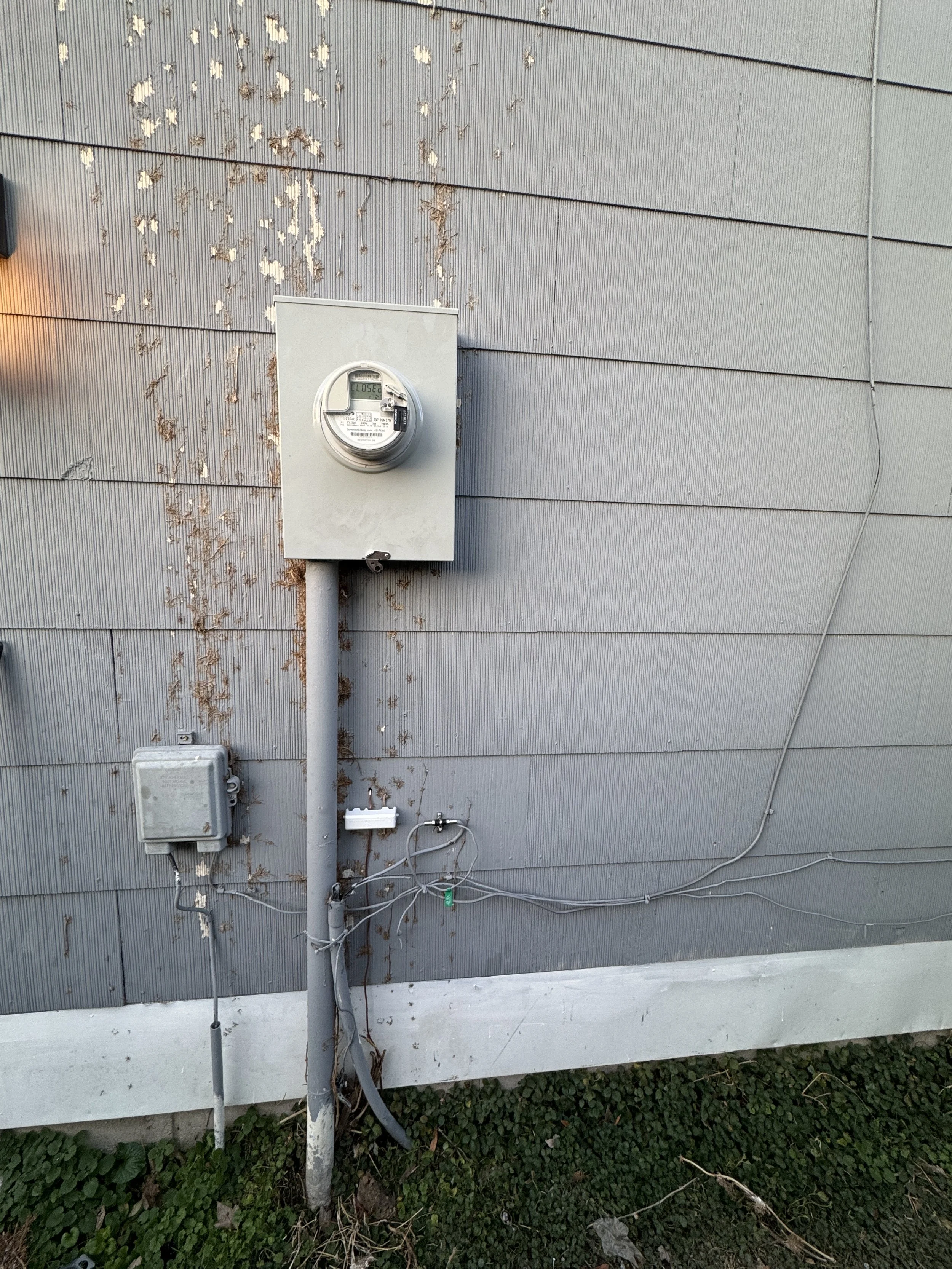 Meter base and a small outdoor enclosure with conduit on the wall of a Portsmouth, VA home