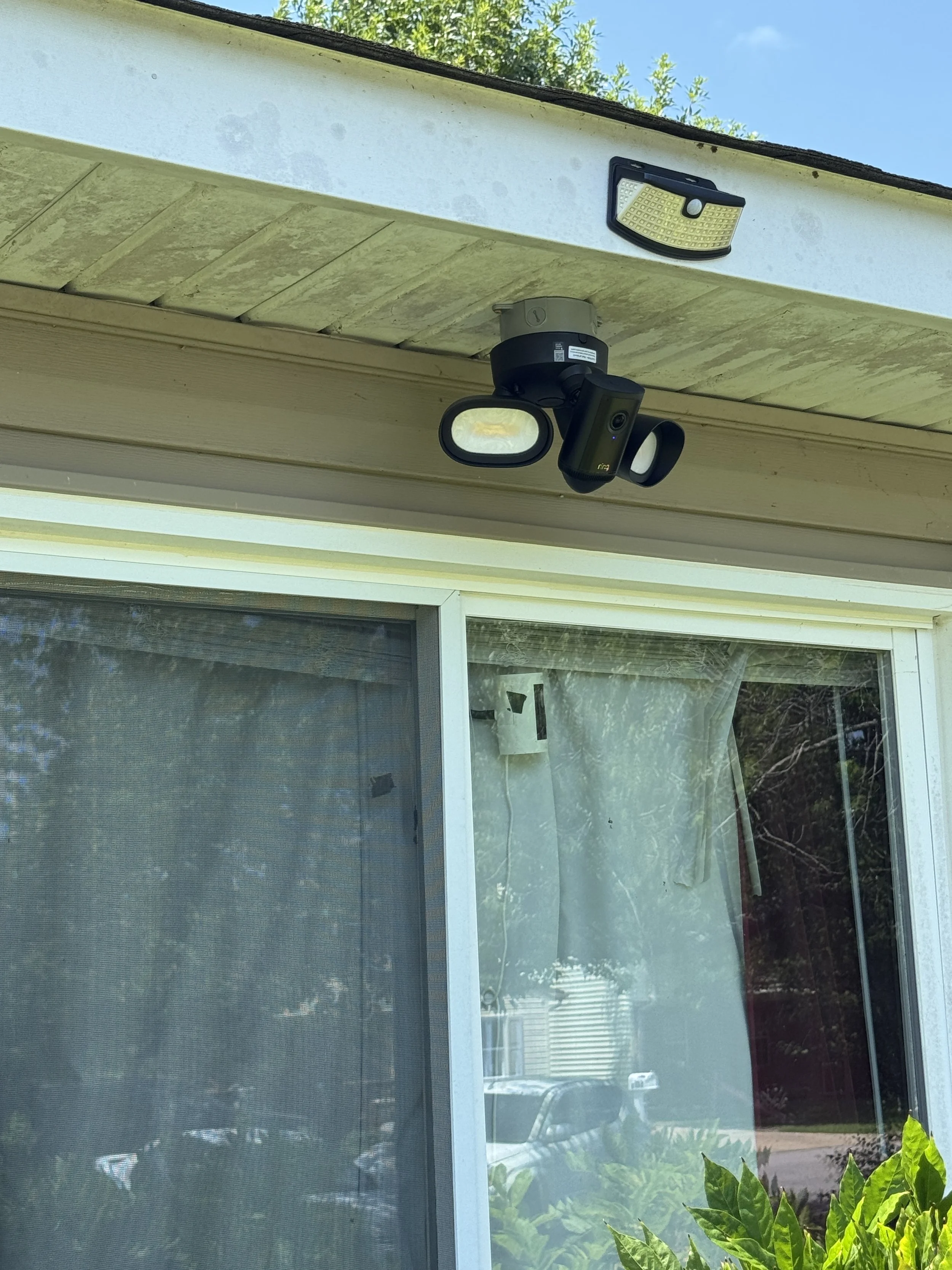Motion floodlight and its daylight sensor mounted under an eave in Suffolk, VA