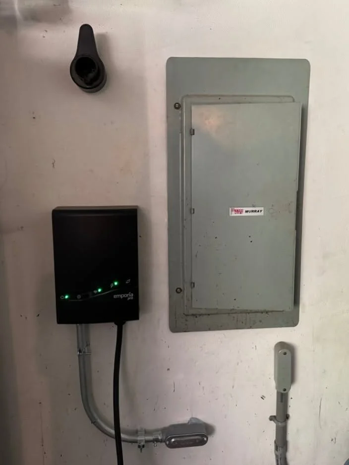 Whole-home surge protective device beside a residential panel, indicator lit