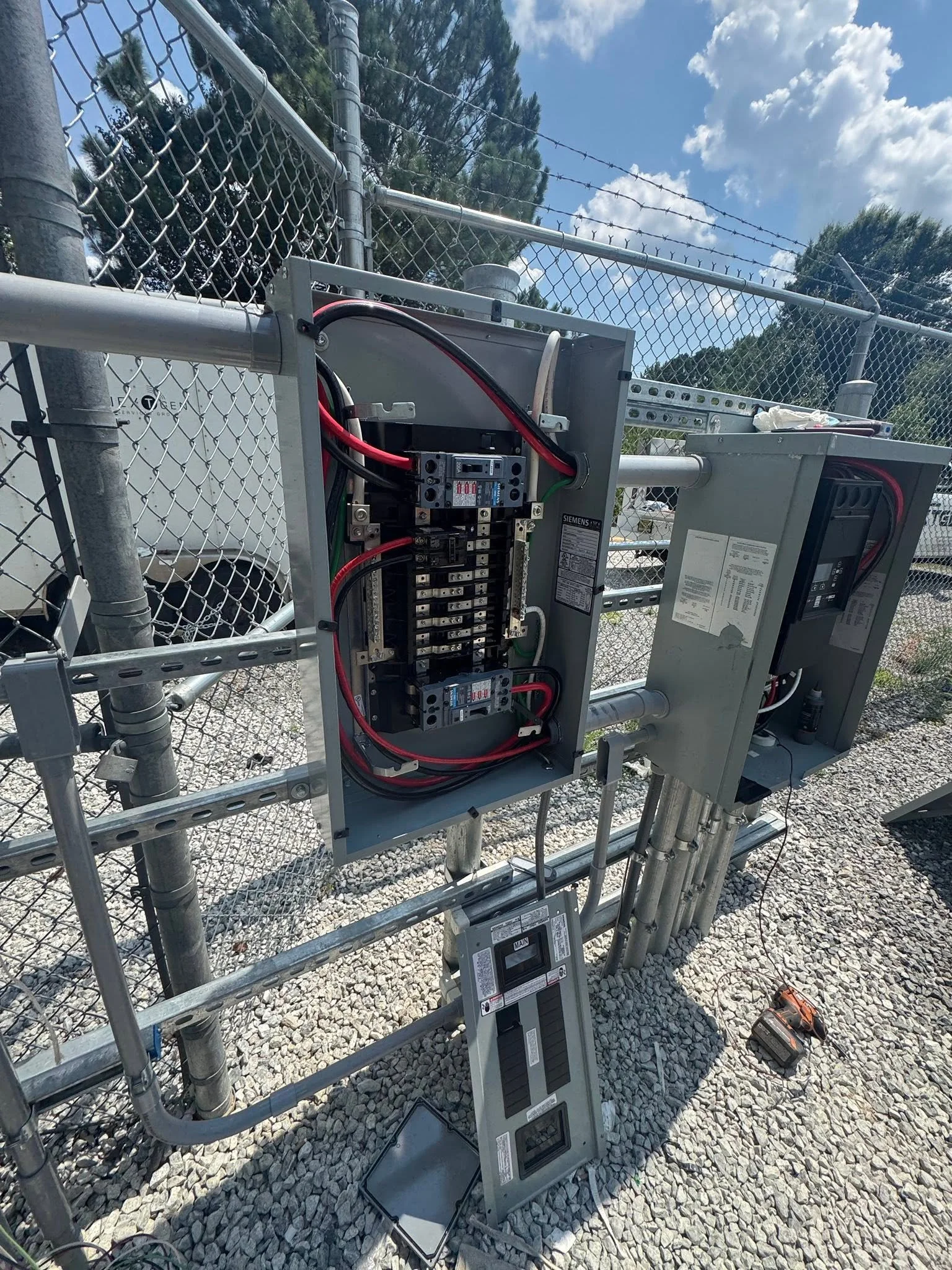Panel and metering equipment on gravel inside a chain-link enclosure