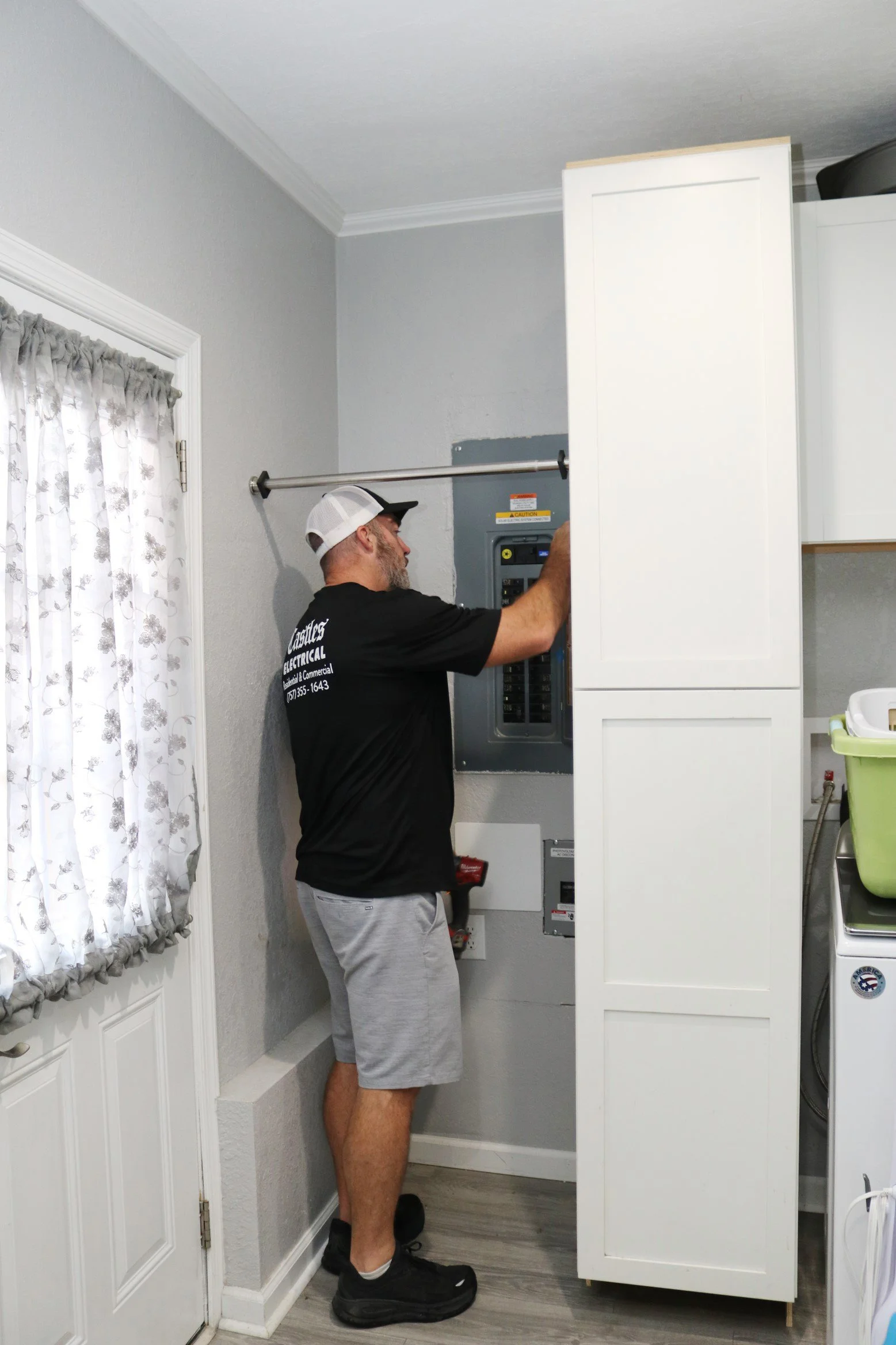 Castles Electrical electrician at a panel boxed in beside a cabinet in a Chesapeake, VA home