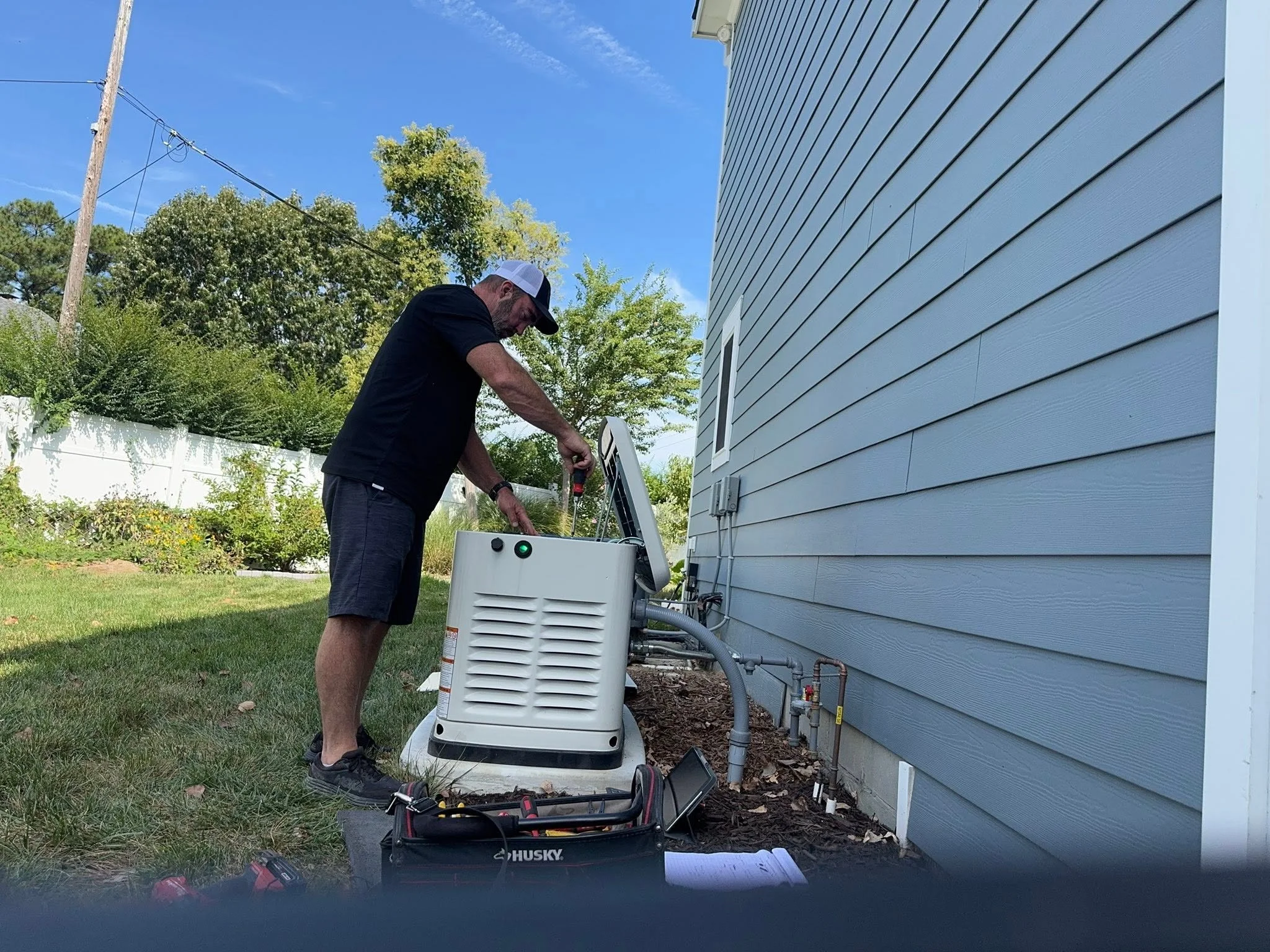 Castles Electrical electrician working at a standby generator beside a building