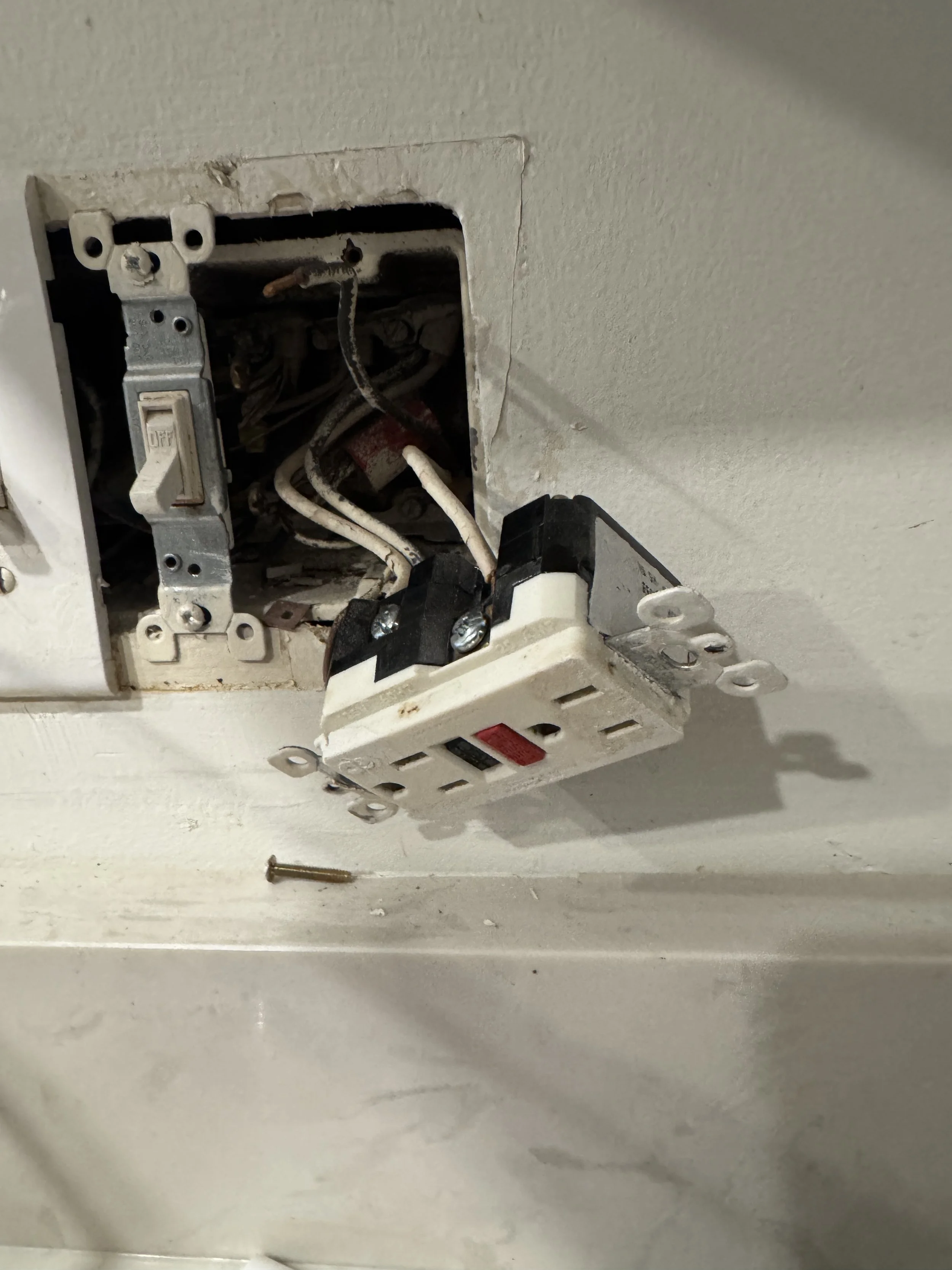 Kitchen receptacle pulled from its box with the connections behind it exposed