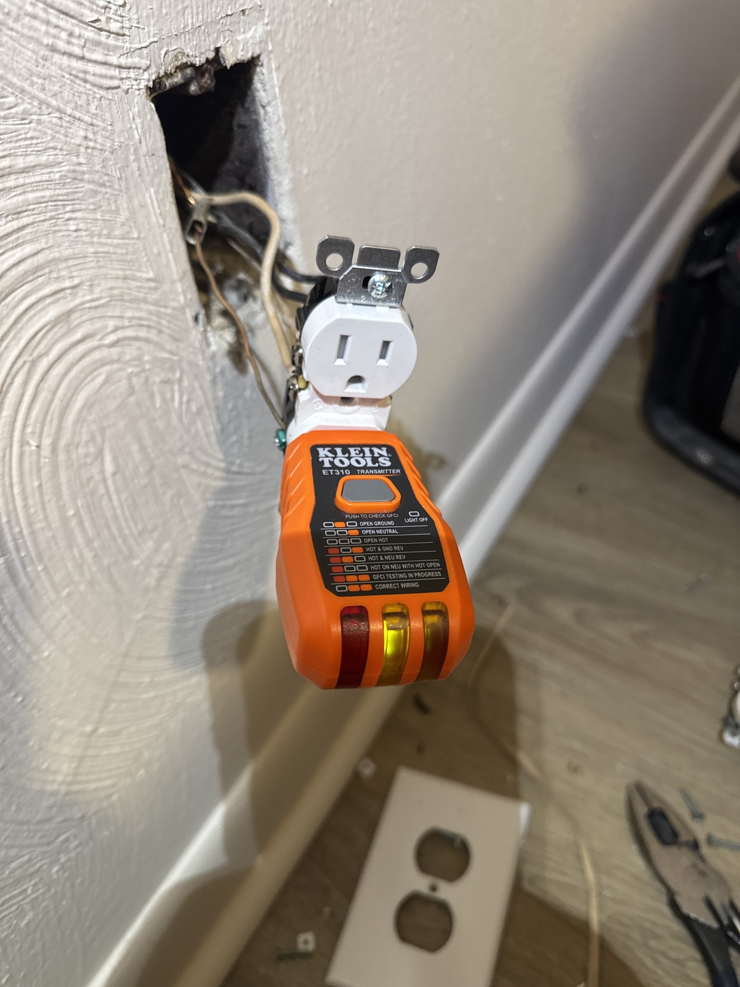 Replacement receptacle held at an opened box above an older two-slot outlet in a Portsmouth, VA home