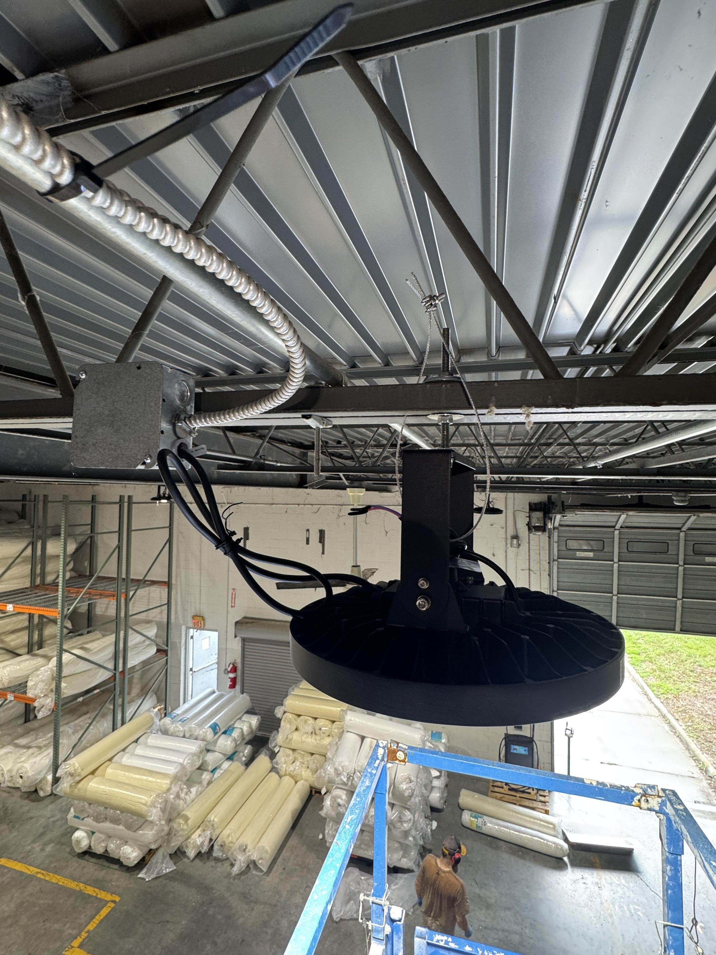 High-bay LED fixture hung from the structure during a lighting retrofit