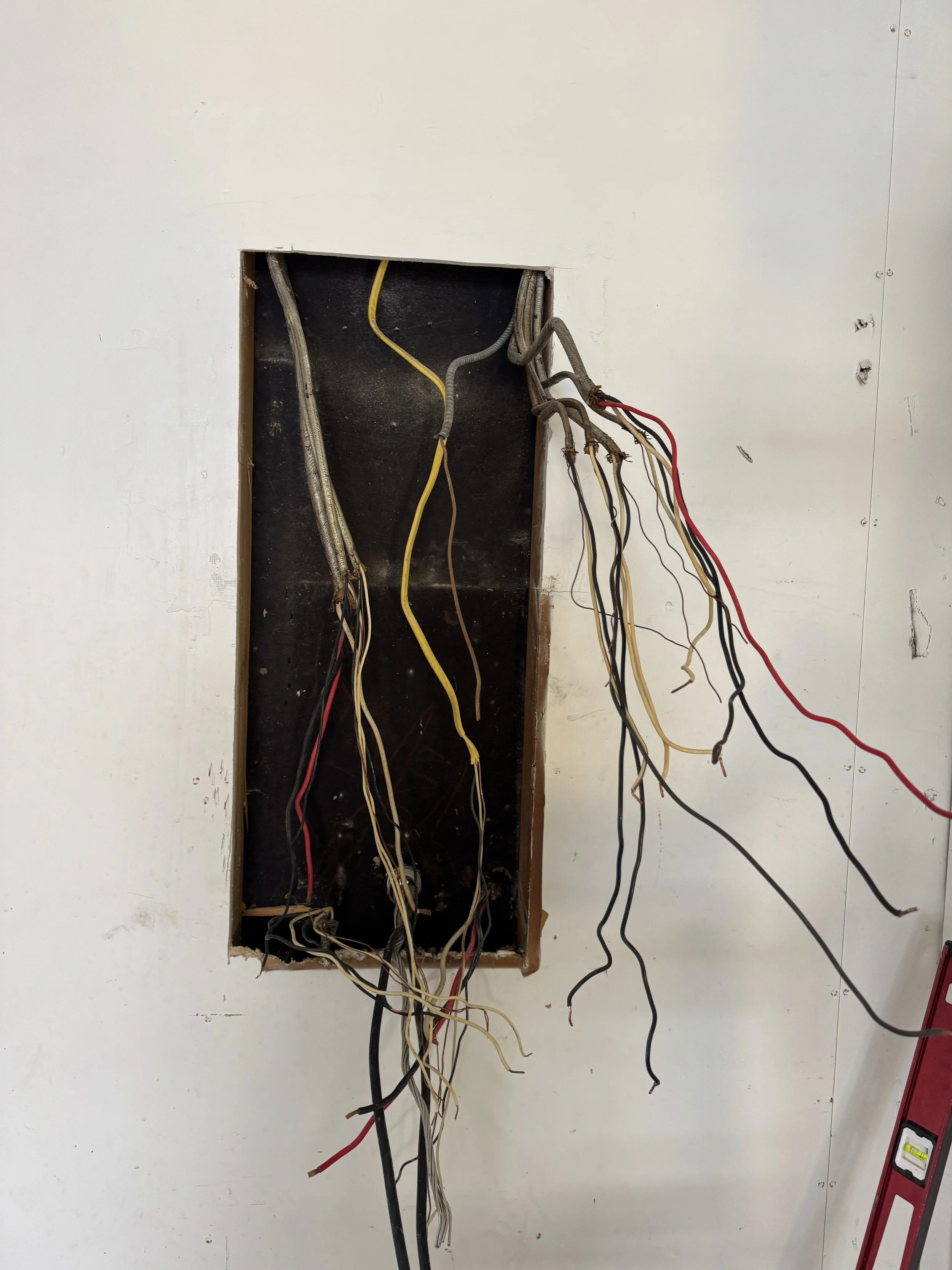 Opened wall cavity with a bundle of circuit conductors drawn out of it