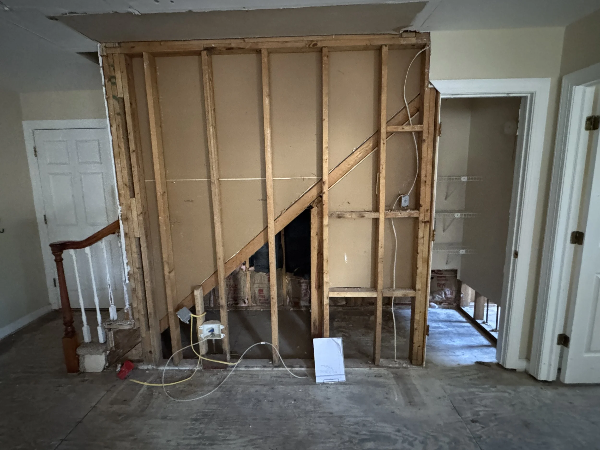 Wall opened back to the studs beside a staircase in an older Portsmouth, VA home