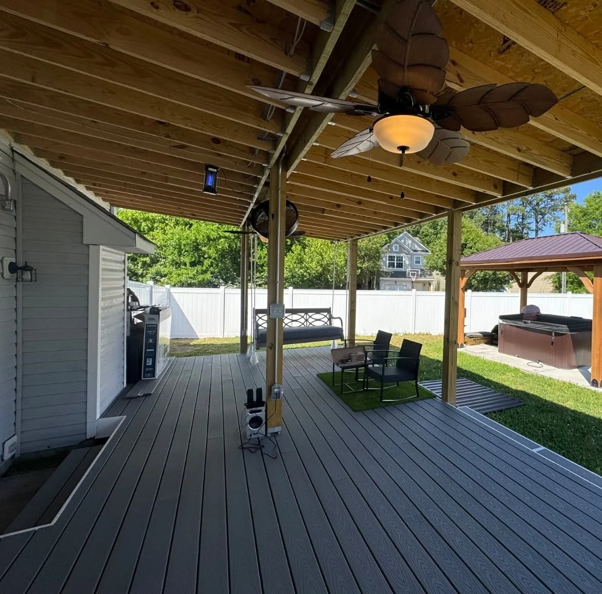 Warm ceiling fan light over a covered porch facing the yard in Suffolk, VA