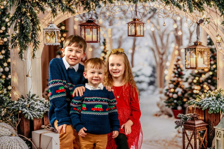 Three siblings posing in a winter Christmas studio set