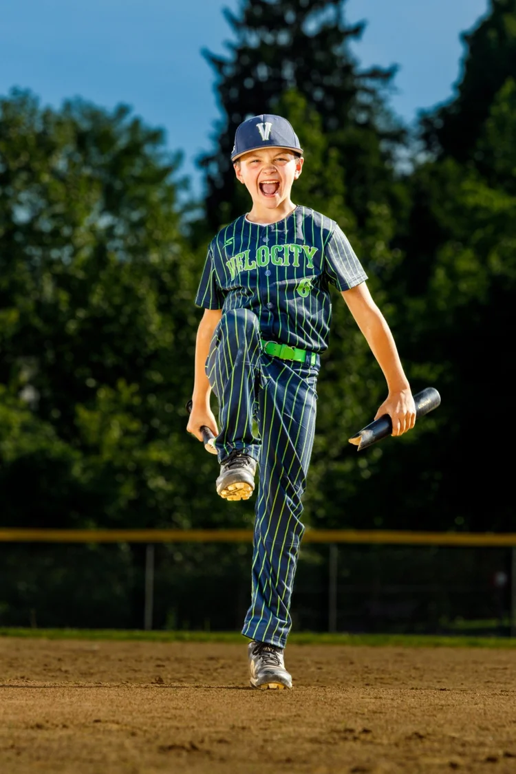 Youth baseball player posing with bats on the field