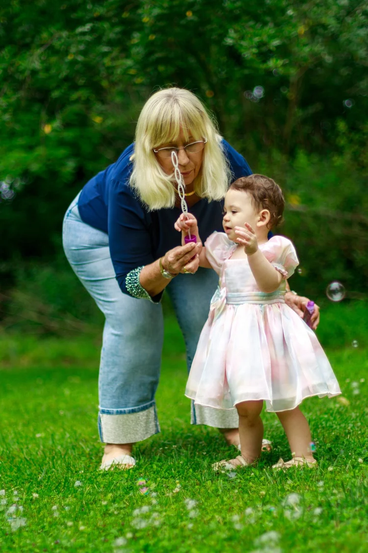 Grandmother and toddler blowing bubbles outdoors