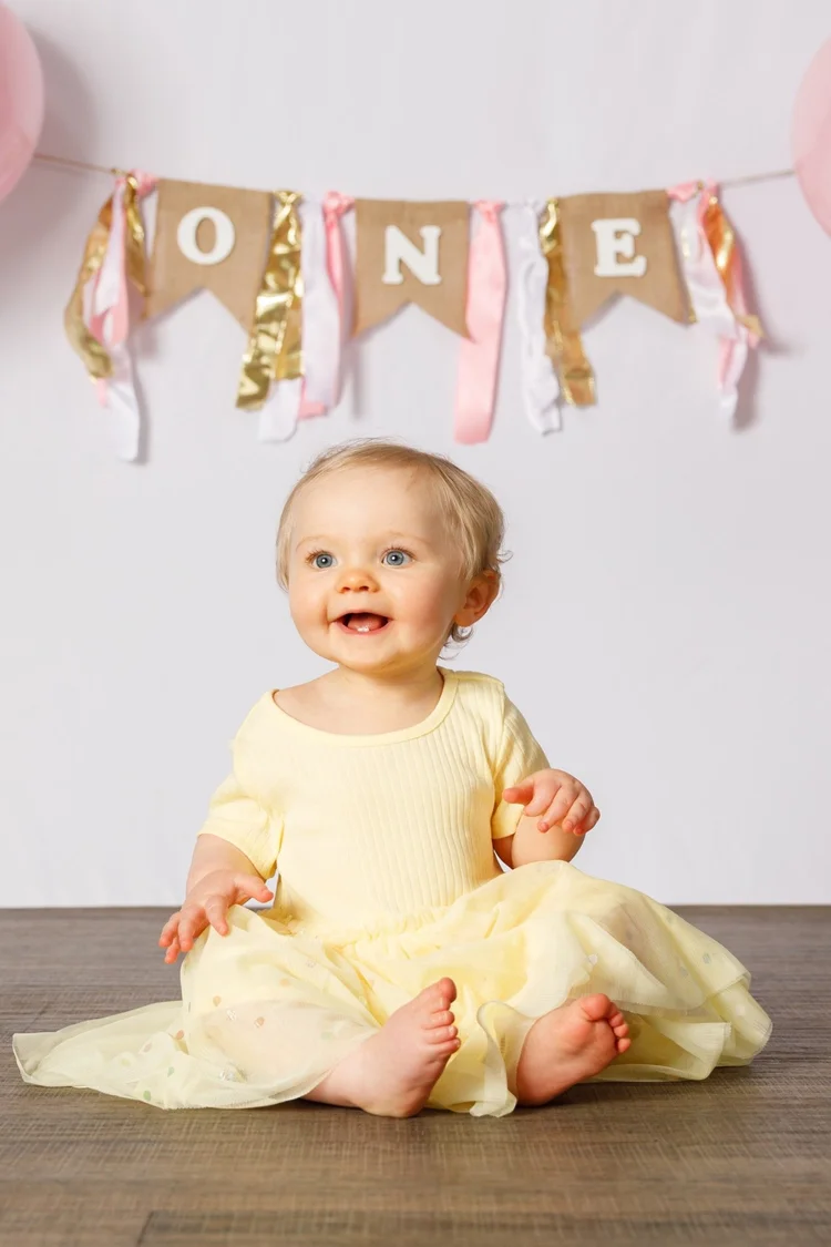 Smiling baby portrait beneath a first birthday banner